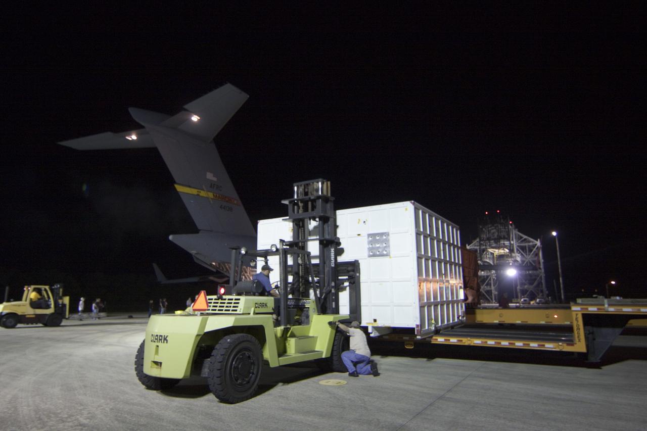 CAPE CANAVERAL, Fla. -- Workers load onto a transporter a container holding the back shell, one of the first three elements for NASA's Mars Science Laboratory (MSL), that arrived at NASA Kennedy Space Center's Shuttle Landing Facility.       The cruise stage, back shell and heat shield, the first flight elements to arrive for the MSL mission, were taken to the Payload Hazardous Servicing Facility (PHSF) located in the KSC Industrial Area to begin processing. The Curiosity rover will arrive next month.    A United Launch Alliance Atlas V-541 configuration will be used to loft MSL into space. Curiosity’s 10 science instruments are designed to search for evidence on whether Mars has had environments favorable to microbial life, including chemical ingredients for life.  The unique rover will use a laser to look inside rocks and release its gasses so that the rover’s spectrometer can analyze and send the data back to Earth. MSL is scheduled to launch from Cape Canaveral Air Force Station in Florida Nov. 25 with a window extending to Dec. 18 and arrival at Mars Aug. 2012. For more information, visit http://www.nasa.gov/msl. Photo credit: NASA/Troy Cryder
