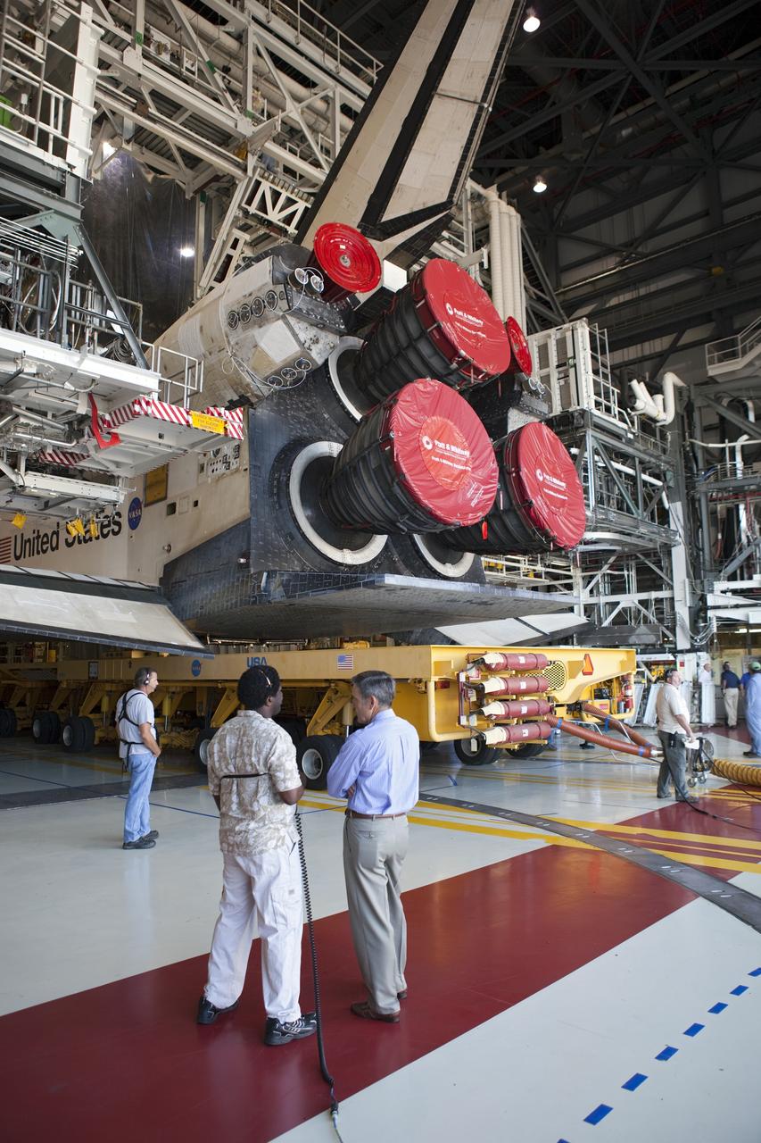 CAPE CANAVERAL, Fla. -- Center Director Bob Cabana (right) speaks with a worker in Orbiter Processing Facility-1 at NASA's Kennedy Space Center in Florida, as shuttle Atlantis is being prepared for it move to the Vehicle Assembly Building (VAB).          The move called "rollover" is a major milestone in processing for the STS-135 mission to the International Space Station. Inside the VAB, the shuttle will be attached to its external fuel tank and solid rocket boosters. Commander Chris Ferguson, Pilot Doug Hurley and Mission Specialists Sandra Magnus and Rex Walheim are expected to launch in mid July, taking with them the Raffaello multipurpose logistics module packed with supplies, logistics and spare parts. The STS-135 mission also will fly a system to investigate the potential for robotically refueling existing spacecraft and return a failed ammonia pump module to help NASA better understand the failure mechanism and improve pump designs for future systems. STS-135 will be the 33rd flight of Atlantis, the 37th shuttle mission to the space station, and the 135th and final mission of NASA's Space Shuttle Program. For more information visit, www.nasa.gov/mission_pages/shuttle/shuttlemissions/sts135/index.html. Photo credit: NASA/Dimitri Gerondidakis