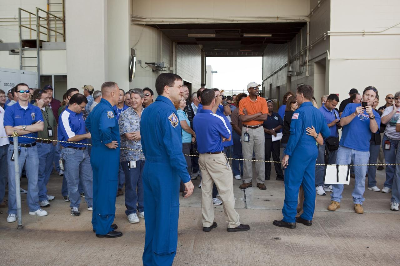 CAPE CANAVERAL, Fla. -- Kennedy employees gather to watch shuttle Atlantis' rollover from Orbiter Processing Facility-1 to the Vehicle Assembly Building (VAB) at NASA's Kennedy Space Center in Florida. In this image are three of the STS-135 crew members; Pilot Doug Hurley (left), Mission Specialist Rex Walheim and Commander Chris Ferguson.        The move called "rollover" is a major milestone in processing for the STS-135 mission to the International Space Station. Inside the VAB, the shuttle will be attached to its external fuel tank and solid rocket boosters. Commander Chris Ferguson, Pilot Doug Hurley and Mission Specialists Sandra Magnus and Rex Walheim are expected to launch in mid July, taking with them the Raffaello multipurpose logistics module packed with supplies, logistics and spare parts. The STS-135 mission also will fly a system to investigate the potential for robotically refueling existing spacecraft and return a failed ammonia pump module to help NASA better understand the failure mechanism and improve pump designs for future systems. STS-135 will be the 33rd flight of Atlantis, the 37th shuttle mission to the space station, and the 135th and final mission of NASA's Space Shuttle Program. For more information visit, www.nasa.gov/mission_pages/shuttle/shuttlemissions/sts135/index.html. Photo credit: NASA/Dimitri Gerondidakis