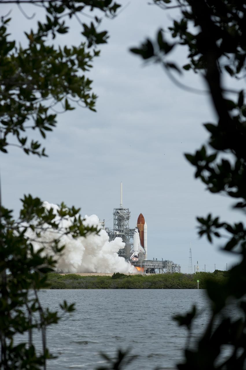 CAPE CANAVERAL, Fla. -- Seen through the foliage from across the Turn Basin, space shuttle Endeavour's solid rocket boosters roar to life at Launch Pad 39A at NASA's Kennedy Space Center in Florida.        Endeavour began its final flight, the STS-134 mission to the International Space Station, at 8:56 a.m. EDT on May 16. Endeavour and its six-member crew will deliver the Alpha Magnetic Spectrometer-2 (AMS), Express Logistics Carrier-3, a high-pressure gas tank and additional spare parts for the Dextre robotic helper to the space station. For more information visit, www.nasa.gov/mission_pages/shuttle/shuttlemissions/sts134/index.html. Photo credit: NASA/Sandra Joseph and Kevin O'Connell