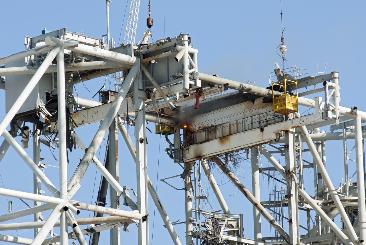 CAPE CANAVERAL, Fla. -- A large crane suspends a basket where a worker is dismantling a section of the rotating service structure on Launch Pad 39B at NASA's Kennedy Space Center in Florida. In 2009, the pad was no longer needed for the shuttle program, so it is being restructured for future use. Its new design will feature a "clean pad" for rockets to come with their own launcher, making it more versatile for a number of vehicles. The new lightning protection system, which was in place for the October 2009 launch of Ares I-X, will remain. For information on NASA's future plans, visit www.nasa.gov. Photo credit: NASA/Jim Grossmann