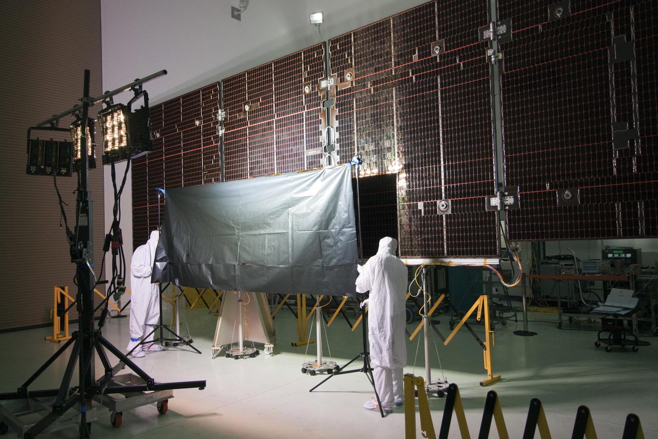 CAPE CANAVERAL, Fla. -- In a clean-room environment at Astrotech's payload processing facility in Titusville, Fla. technicians conduct an illumination test on the solar array panels for NASA's Juno spacecraft.        Juno is scheduled to launch aboard a United Launch Alliance Atlas V rocket from Cape Canaveral, Fla. Aug. 5.The solar-powered spacecraft will orbit Jupiter's poles 33 times to find out more about the gas giant's origins, structure, atmosphere and magnetosphere and investigate the existence of a solid planetary core. For more information visit: www.nasa.gov/juno. Photo credit: NASA/Jack Pfaller