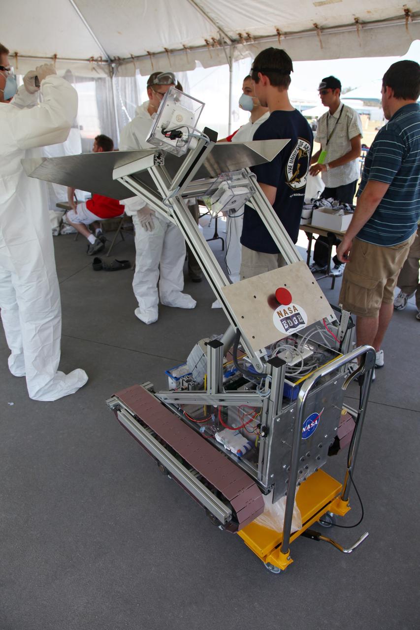 CAPE CANAVERAL, Fla. -- University students prepare their remote controlled or autonomous excavator, called a lunabot, in a tent next to the "Lunarena" at the Kennedy Space Center Visitor Complex.              Thirty-six teams of undergraduate and graduate students from the United States, Bangladesh, Canada, Colombia and India will participate in NASA's Lunabotics Mining Competition May 26 - 28 at the agency's Kennedy Space Center in Florida. The competition is designed to engage and retain students in science, technology, engineering and mathematics (STEM). Teams will maneuver their remote controlled or autonomous excavators, called lunabots, in about 60 tons of ultra-fine simulated lunar soil, called BP-1. The competition is an Exploration Systems Mission Directorate project managed by Kennedy's Education Division. The event also provides a competitive environment that could result in innovative ideas and solutions for NASA's future excavation of the moon. Photo credit: NASA/Frankie Martin