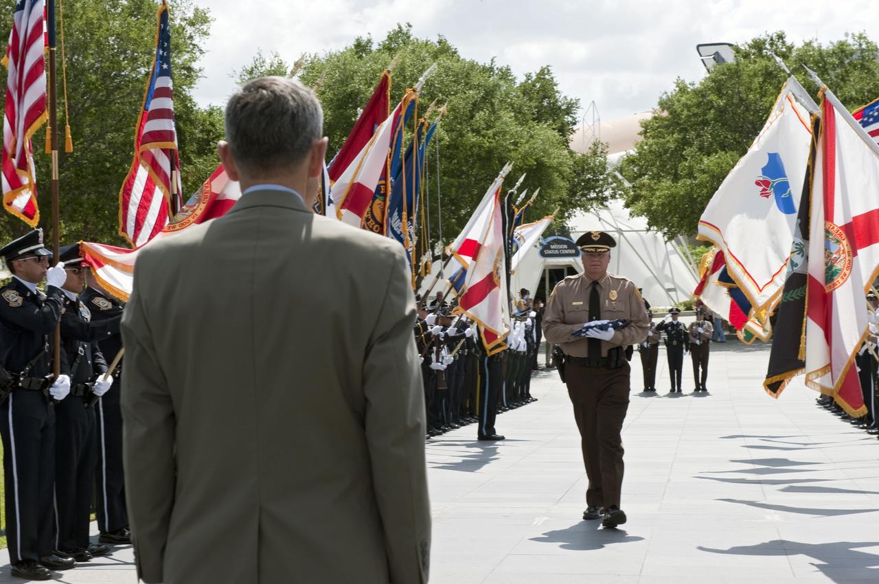 CAPE CANAVERAL, Fla. -- At NASA's Kennedy Space Center Visitor Complex, Center Director Bob Cabana stands at the base of the Astronaut Memorial Mirror to accept the U.S. Honor Flag presented to him by James Loftus (right), director of the Miami-Dade Police Department.            The flag is presented to NASA to be prepared to fly aboard space shuttle Atlantis on the Space Shuttle Program's final mission, STS-135. The U.S. Honor Flag has been flown nationwide, at Ground Zero and throughout the world to honor heroes who have lost their lives while serving their community and country, including police officers, firefighters, members of the Armed Forces and astronauts. More than 100 honor guard members traveled to the Space Coast to take part in the ceremony. After the flag returns to Earth, it will continue as a traveling memorial. Photo credit: NASA/Kim Shiflett