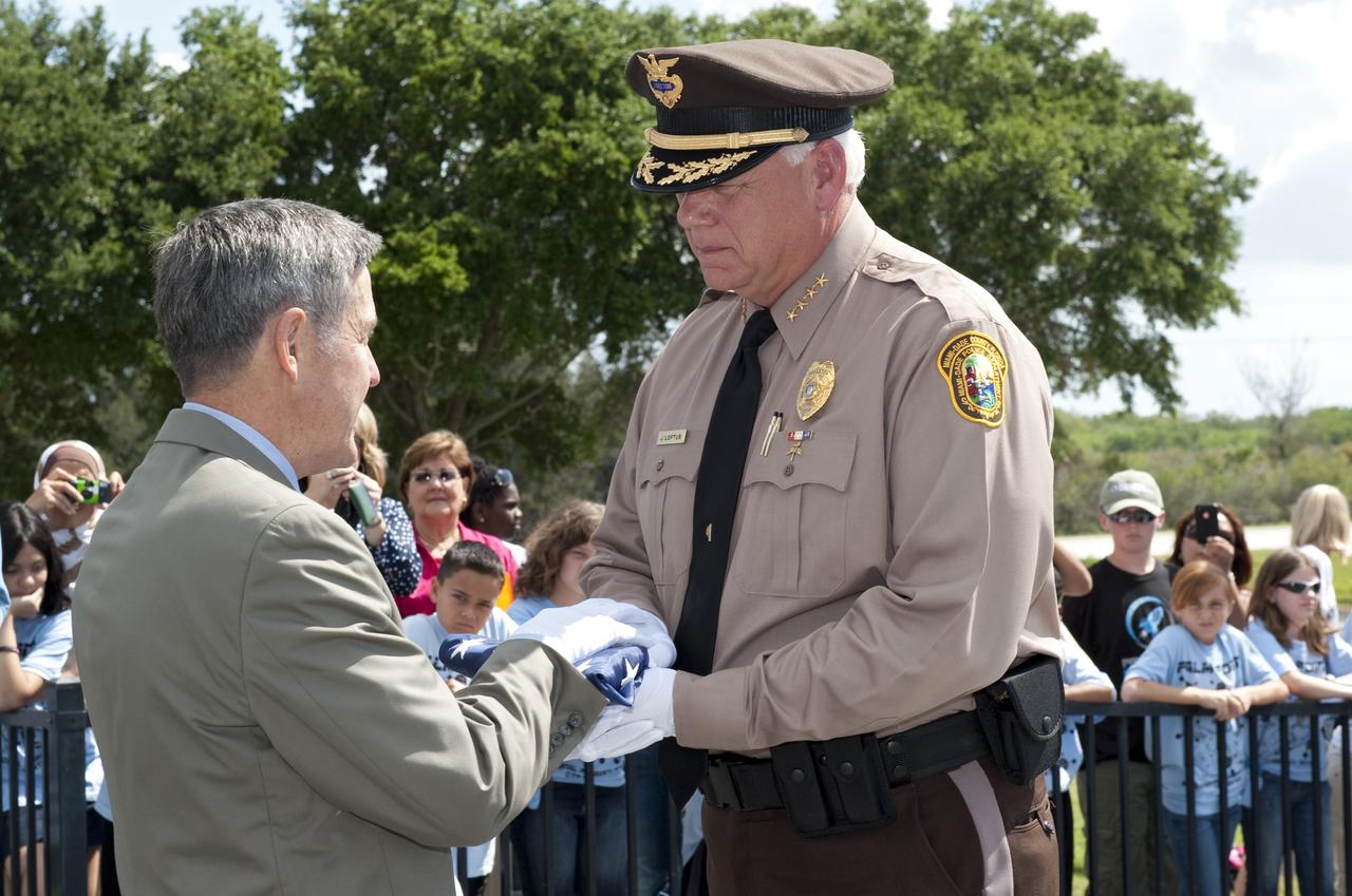 CAPE CANAVERAL, Fla. -- At the base of the Astronaut Memorial Mirror at NASA's Kennedy Space Center Visitor Complex, Center Director Bob Cabana accepts the U.S. Honor Flag presented to him by James Loftus (right), director of the Miami-Dade Police Department.         The flag is presented to NASA to be prepared to fly aboard space shuttle Atlantis on the Space Shuttle Program's final mission, STS-135. The U.S. Honor Flag has been flown nationwide, at Ground Zero and throughout the world to honor heroes who have lost their lives while serving their community and country, including police officers, firefighters, members of the Armed Forces and astronauts. More than 100 honor guard members traveled to the Space Coast to take part in the ceremony. After the flag returns to Earth, it will continue as a traveling memorial. Photo credit: NASA/Kim Shiflett