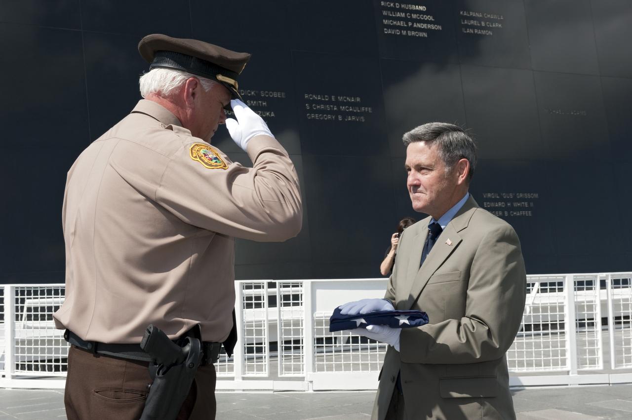 CAPE CANAVERAL, Fla. -- At the base of the Astronaut Memorial Mirror at NASA's Kennedy Space Center Visitor Complex, James Loftus (left), director of the Miami-Dade Police Department Center salutes as Director Bob Cabana accepts the U.S. Honor Flag.       The flag is presented to NASA to be prepared to fly aboard space shuttle Atlantis on the Space Shuttle Program's final mission, STS-135. The U.S. Honor Flag has been flown nationwide, at Ground Zero and throughout the world to honor heroes who have lost their lives while serving their community and country, including police officers, firefighters, members of the Armed Forces and astronauts. More than 100 honor guard members traveled to the Space Coast to take part in the ceremony. After the flag returns to Earth, it will continue as a traveling memorial. Photo credit: NASA/Kim Shiflett