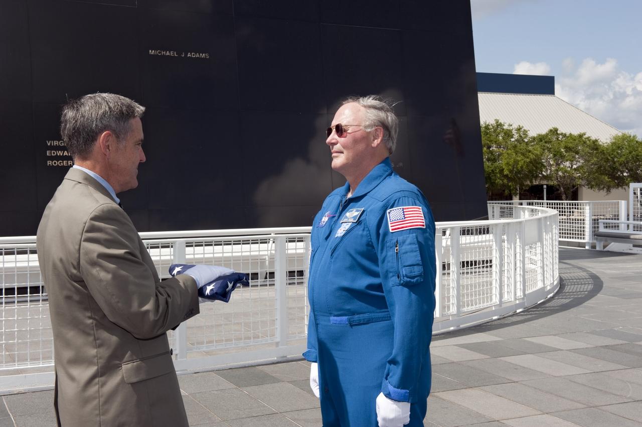 CAPE CANAVERAL, Fla. -- At NASA's Kennedy Space Center Visitor Complex's Astronaut Memorial Mirror, Center Director Bob Cabana presents the U.S. Honor Flag to Jerry Ross, chief of the Vehicle Integration Test Office.    The flag is presented to NASA to be prepared to fly aboard space shuttle Atlantis on the Space Shuttle Program's final mission, STS-135. The U.S. Honor Flag has been flown nationwide, at Ground Zero and throughout the world to honor heroes who have lost their lives while serving their community and country, including police officers, firefighters, members of the Armed Forces and astronauts. More than 100 honor guard members traveled to the Space Coast to take part in the ceremony. After the flag returns to Earth, it will continue as a traveling memorial. Photo credit: NASA/Kim Shiflett