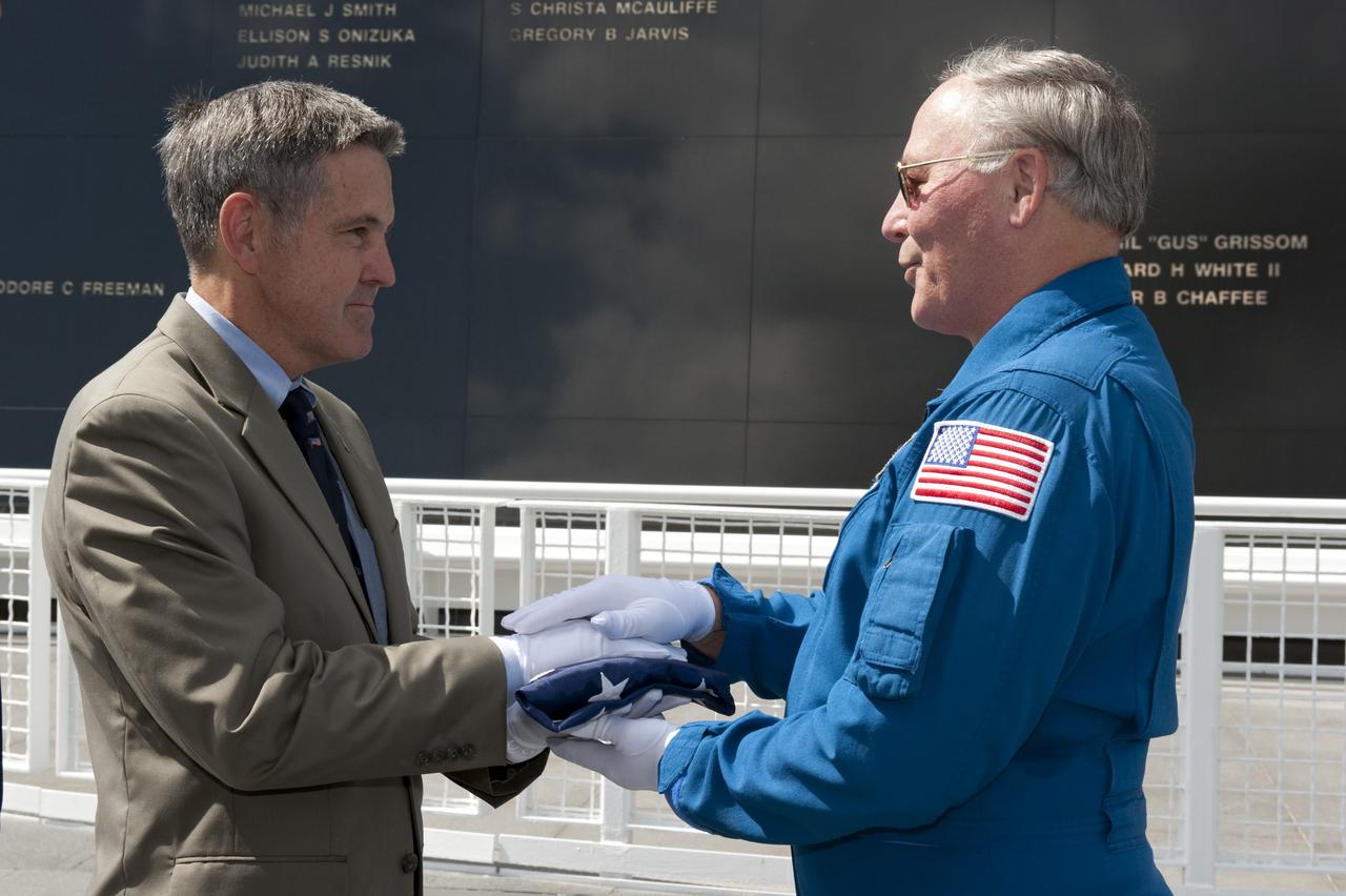 CAPE CANAVERAL, Fla. -- At NASA's Kennedy Space Center Visitor Complex's Astronaut Memorial Mirror, Jerry Ross, chief of the Vehicle Integration Test Office accepts the U.S. Honor Flag presented to him by Center Director Bob Cabana.        The flag is presented to NASA to be prepared to fly aboard space shuttle Atlantis on the Space Shuttle Program's final mission, STS-135. The U.S. Honor Flag has been flown nationwide, at Ground Zero and throughout the world to honor heroes who have lost their lives while serving their community and country, including police officers, firefighters, members of the Armed Forces and astronauts. More than 100 honor guard members traveled to the Space Coast to take part in the ceremony. After the flag returns to Earth, it will continue as a traveling memorial. Photo credit: NASA/Kim Shiflett