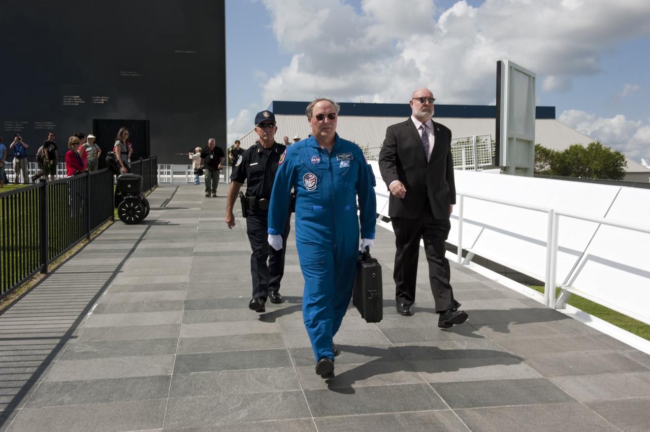 CAPE CANAVERAL, Fla. -- At NASA's Kennedy Space Center Visitor Complex's Astronaut Memorial Mirror, Jerry Ross, chief of the Vehicle Integration Test Office holds onto the secure case containing the U.S. Honor Flag accompanied by Mark Borsi NASA security director (right) and a security guard.           The flag is presented to NASA to be prepared to fly aboard space shuttle Atlantis on the Space Shuttle Program's final mission, STS-135. The U.S. Honor Flag has been flown nationwide, at Ground Zero and throughout the world to honor heroes who have lost their lives while serving their community and country, including police officers, firefighters, members of the Armed Forces and astronauts. More than 100 honor guard members traveled to the Space Coast to take part in the ceremony. After the flag returns to Earth, it will continue as a traveling memorial. Photo credit: NASA/Kim Shiflett