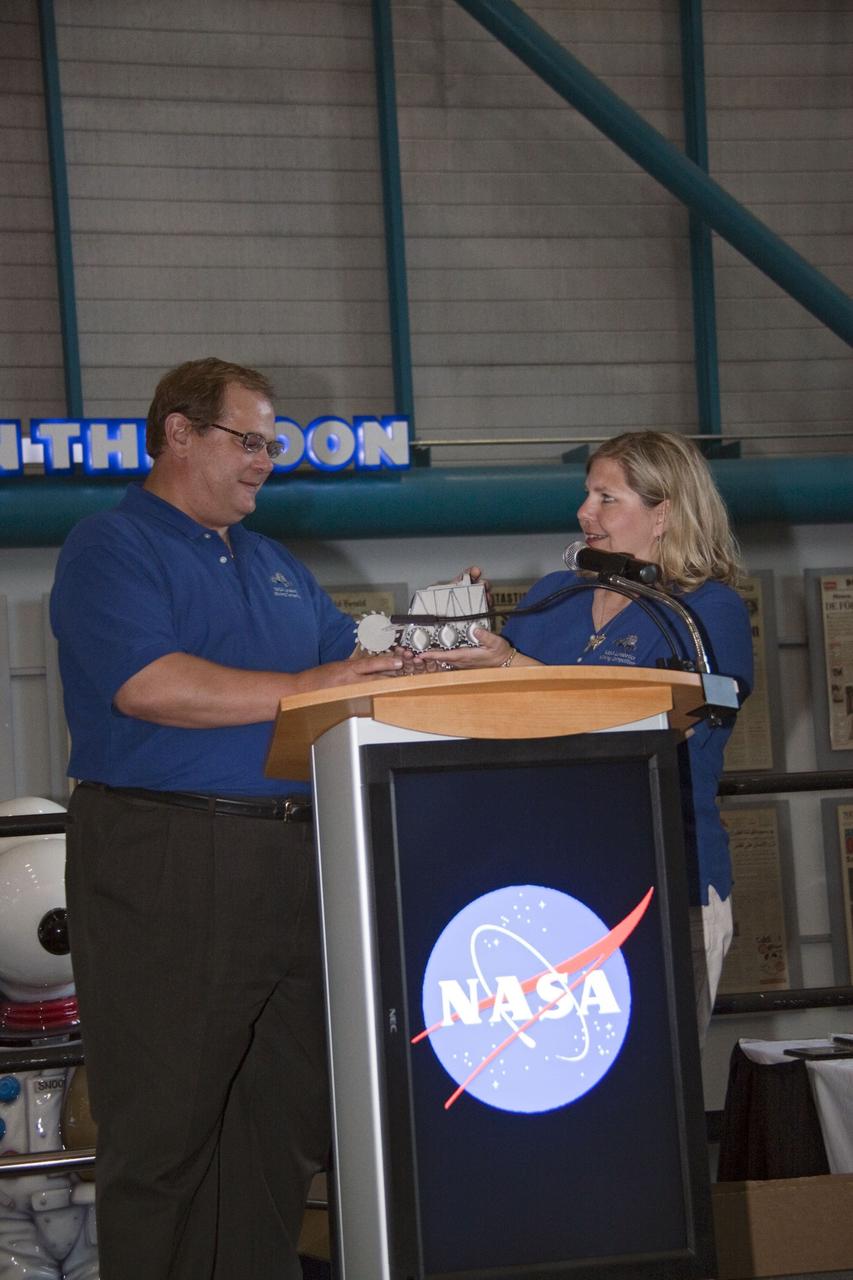 CAPE CANAVERAL, Fla. -- At NASA Kennedy Space Center's Apollo/Saturn V Center, Jerry Hartman, Education Lead with the Exploration Systems Mission Directorate at NASA Headquarters and Susan Sawyer, Lunabotics Project Coordinator with ReDe/Critique, display the trophy the winning team will receive at the award ceremony for NASA's second annual Lunabotics Mining Competition.      Thirty-six teams of undergraduate and graduate students from the United States, Bangladesh, Canada, Colombia and India participated in NASA's Lunabotics Mining Competition May 26 - 28 at the agency's Kennedy Space Center in Florida. The competition is designed to engage and retain students in science, technology, engineering and mathematics (STEM). Teams will maneuver their remote controlled or autonomous excavators, called lunabots, in about 60 tons of ultra-fine simulated lunar soil, called BP-1. The competition is an Exploration Systems Mission Directorate project managed by Kennedy's Education Division. The event also provides a competitive environment that could result in innovative ideas and solutions for NASA's future excavation of the moon. Photo credit: NASA/Jack Pfaller