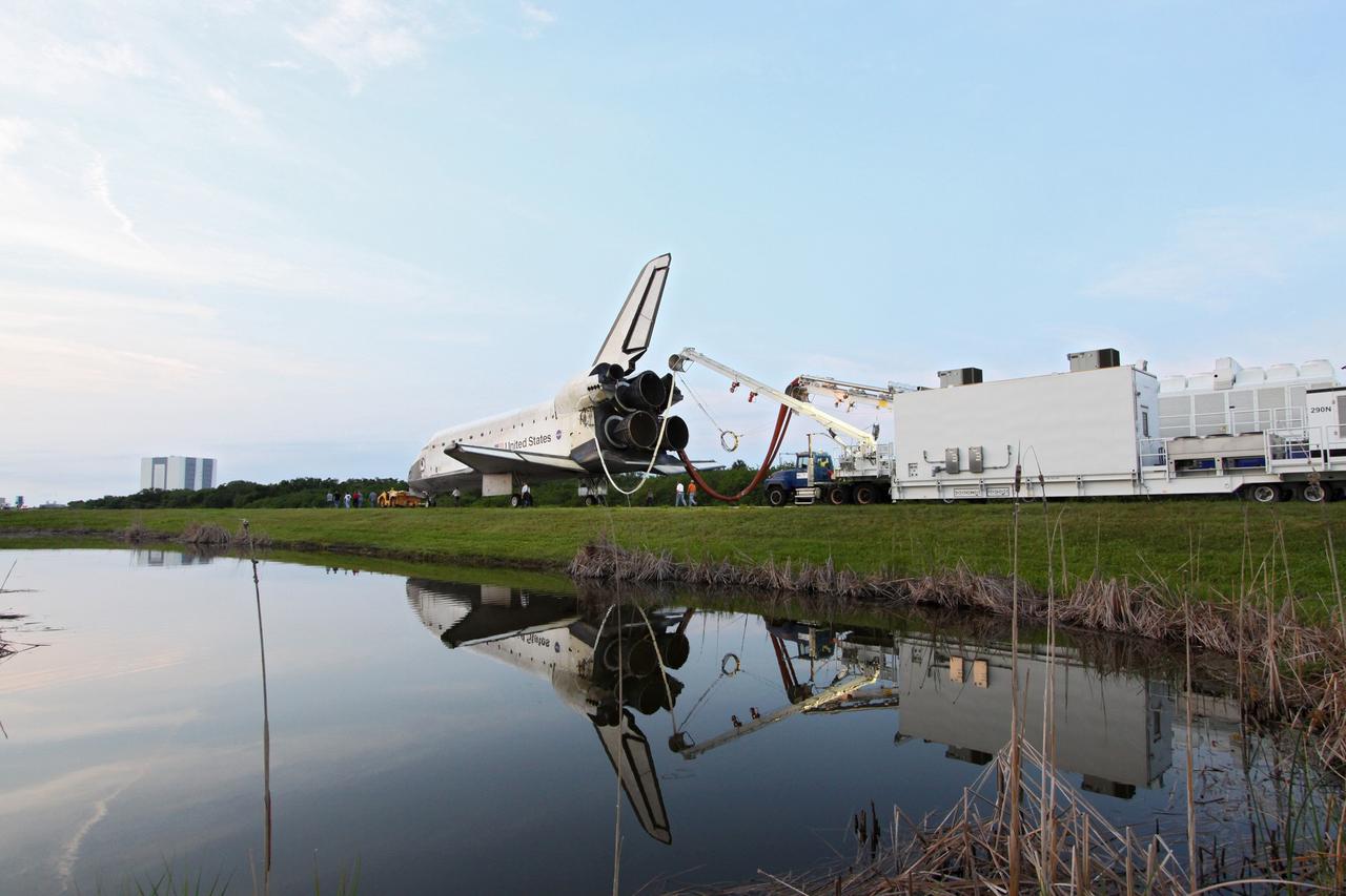 CAPE CANAVERAL, Fla. -- In the early morning hours after landing, space shuttle Endeavour's "towback" vehicle slowly pulls it from the Shuttle Landing Facility to Orbiter Processing Facility-1 at NASA's Kennedy Space Center in Florida. A purge unit that pumps conditioned air into a shuttle after landing is connected to Endeavour's aft end. In the background is the massive Vehicle Assembly Building. Once inside the processing facility, Endeavour will be prepared for future public display.        Endeavour's final return from space completed the 16-day, 6.5-million-mile STS-134 mission. Main gear touchdown was at 2:34:51 a.m. EDT, followed by nose gear touchdown at 2:35:04 a.m., and wheelstop at 2:35:36 a.m.   Endeavour and its crew delivered the Alpha Magnetic Spectrometer-2 (AMS) and the Express Logistics Carrier-3 (ELC-3) to the International Space Station. AMS will help researchers understand the origin of the universe and search for evidence of dark matter, strange matter and antimatter from the station. ELC-3 carried spare parts that will sustain station operations once the shuttles are retired from service. STS-134 was the 25th and final flight for Endeavour, which spent 299 days in space, orbited Earth 4,671 times and traveled 122,883,151 miles. Photo credit: NASA/Jack Pfaller