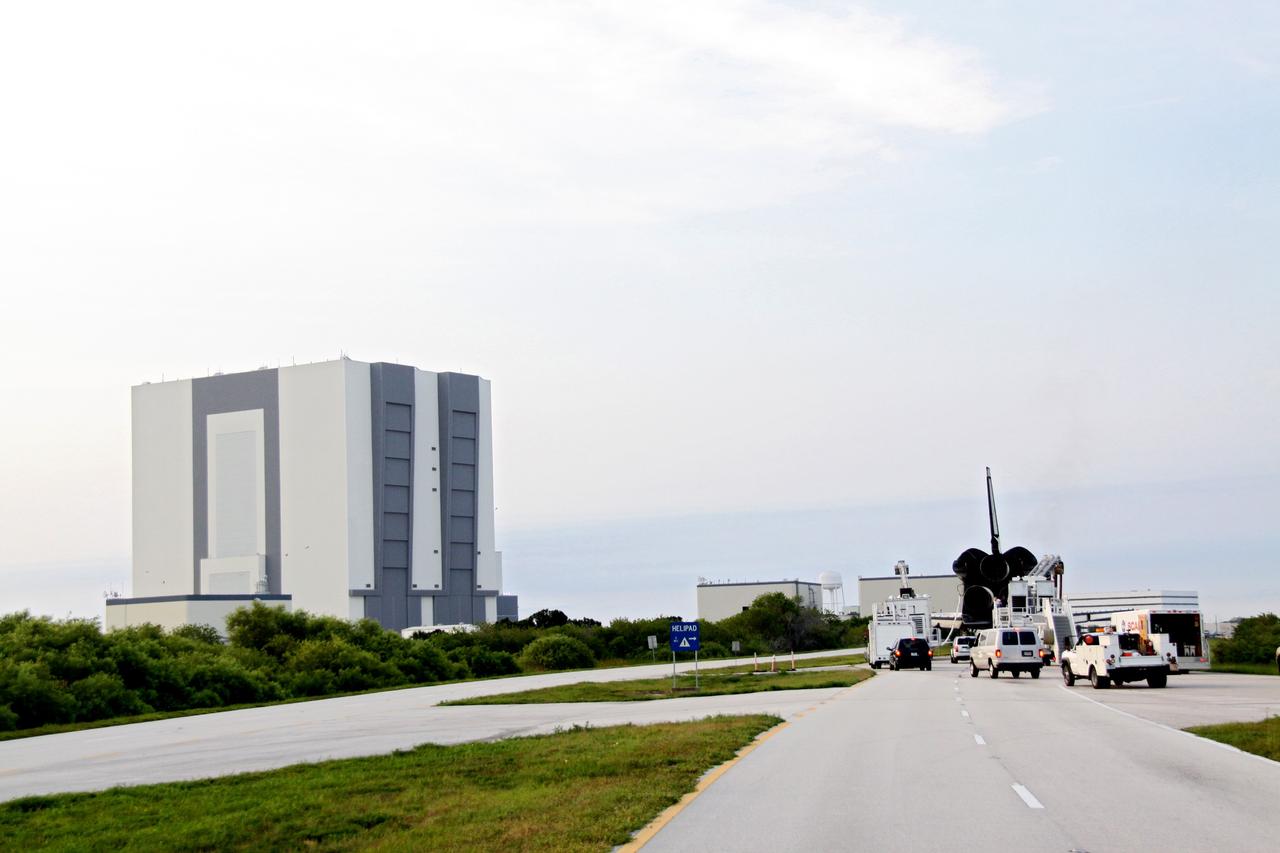 CAPE CANAVERAL, Fla. -- A "towback" vehicle slowly pulls shuttle Endeavour from the Shuttle Landing Facility to Orbiter Processing Facility-1 at NASA's Kennedy Space Center in Florida. A purge unit that pumps conditioned air into a shuttle after landing is connected to Endeavour's aft end. In the background is the massive Vehicle Assembly Building. Once inside the processing facility, Endeavour will be prepared for future public display.              Endeavour's final return from space completed the 16-day, 6.5-million-mile STS-134 mission. Main gear touchdown was at 2:34:51 a.m. EDT, followed by nose gear touchdown at 2:35:04 a.m., and wheelstop at 2:35:36 a.m.   Endeavour and its crew delivered the Alpha Magnetic Spectrometer-2 (AMS) and the Express Logistics Carrier-3 (ELC-3) to the International Space Station. AMS will help researchers understand the origin of the universe and search for evidence of dark matter, strange matter and antimatter from the station. ELC-3 carried spare parts that will sustain station operations once the shuttles are retired from service. STS-134 was the 25th and final flight for Endeavour, which spent 299 days in space, orbited Earth 4,671 times and traveled 122,883,151 miles. Photo credit: NASA/Jack Pfaller