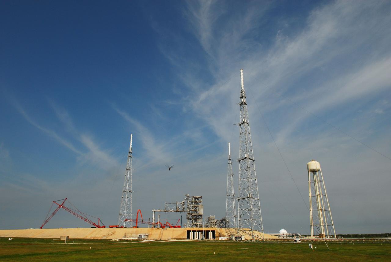 Cape Canaveral, Fla. -- Workers using a large crane dismantle the final sections of the rotating service structure on Launch Pad 39B at NASA's Kennedy Space Center in Florida. A dragonfly passing across the camera lens (center) pays no attention to the pad's deconstruction in progress. In 2009, the pad was no longer needed for the shuttle program, so it is being restructured for future use. Its new design will feature a "clean pad" for rockets to come with their own launcher, making it more versatile for a number of vehicles. The new lightning protection system, which was in place for the October 2009 launch of Ares I-X, will remain. For information on NASA's future plans, visit www.nasa.gov. Photo credit: NASA/Jim Grossmann