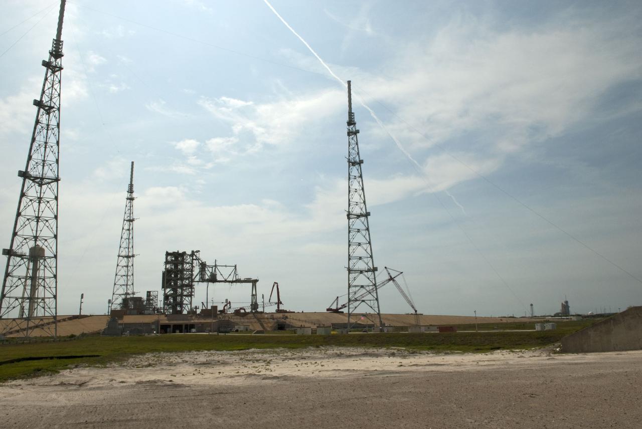 Cape Canaveral, Fla. -- Workers using a large crane dismantle the final sections of the rotating service structure on Launch Pad 39B at NASA's Kennedy Space Center in Florida. Space shuttle Atlantis can be seen on Launch Pad 39A (far right background) as it is being prepared for the final space shuttle mission, STS-135. In 2009, the pad was no longer needed for the shuttle program, so it is being restructured for future use. Its new design will feature a "clean pad" for rockets to come with their own launcher, making it more versatile for a number of vehicles. The new lightning protection system, which was in place for the October 2009 launch of Ares I-X, will remain. For information on NASA's future plans, visit www.nasa.gov. Photo credit: NASA/Jim Grossmann