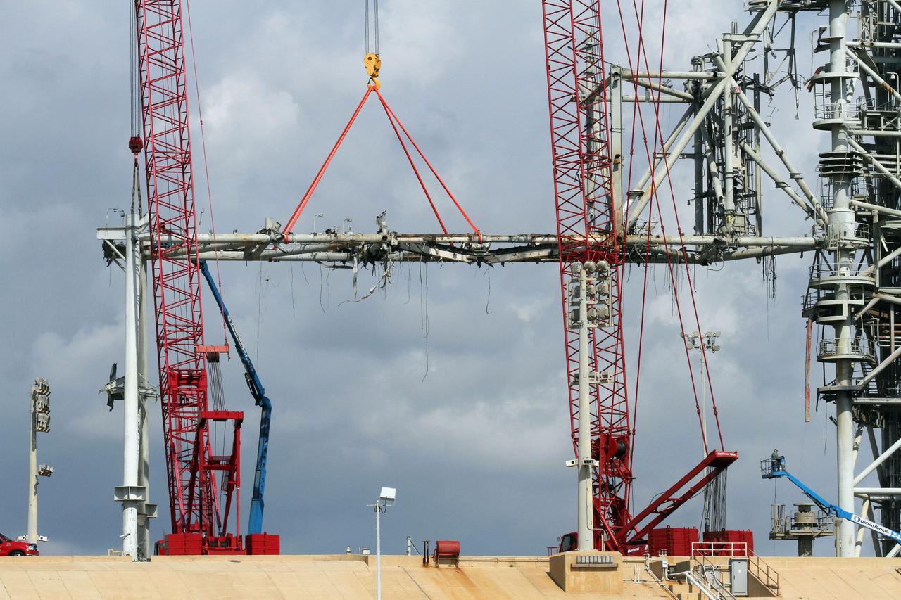Cape Canaveral, Fla. -- Workers using a large crane remove the access arm section of the rotating service structure on Launch Pad 39B at NASA's Kennedy Space Center in Florida. In 2009, the pad was no longer needed for the shuttle program, so it is being restructured for future use. Its new design will feature a "clean pad" for rockets to come with their own launcher, making it more versatile for a number of vehicles. The new lightning protection system, which was in place for the October 2009 launch of Ares I-X, will remain. For information on NASA's future plans, visit www.nasa.gov. Photo credit: NASA/Cory Huston