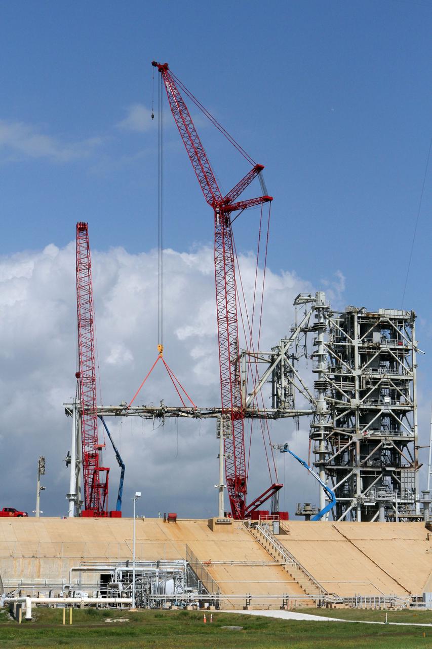 Cape Canaveral, Fla. -- Workers using a large crane remove the access arm section of the rotating service structure on Launch Pad 39B at NASA's Kennedy Space Center in Florida. In 2009, the pad was no longer needed for the shuttle program, so it is being restructured for future use. Its new design will feature a "clean pad" for rockets to come with their own launcher, making it more versatile for a number of vehicles. The new lightning protection system, which was in place for the October 2009 launch of Ares I-X, will remain. For information on NASA's future plans, visit www.nasa.gov. Photo credit: NASA/Cory Huston