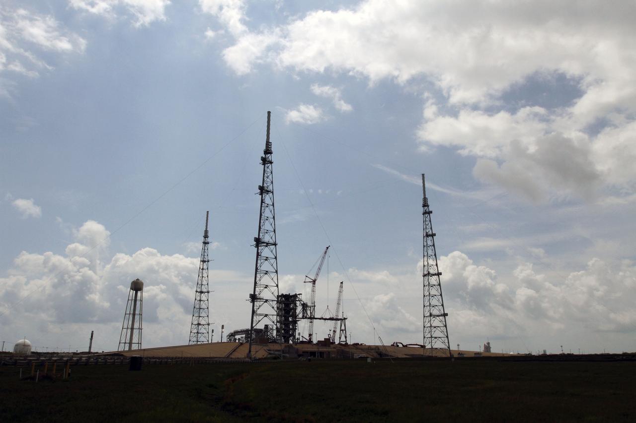 Cape Canaveral, Fla. -- Workers using a large crane remove the access arm section of the rotating service structure on Launch Pad 39B at NASA's Kennedy Space Center in Florida. Space shuttle Atlantis can be seen on Launch Pad 39A (far right background) as it is being prepared for the final space shuttle mission, STS-135. In 2009, the pad was no longer needed for the shuttle program, so it is being restructured for future use. Its new design will feature a "clean pad" for rockets to come with their own launcher, making it more versatile for a number of vehicles. The new lightning protection system, which was in place for the October 2009 launch of Ares I-X, will remain. For information on NASA's future plans, visit www.nasa.gov. Photo credit: NASA/Cory Huston