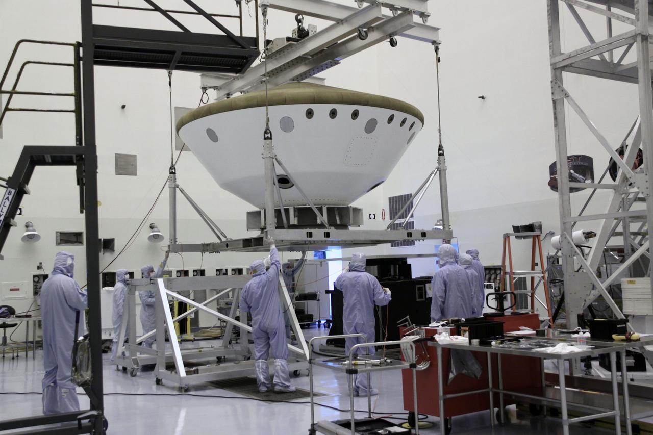 Cape Canaveral, Fla. -- At the Payload Hazardous Servicing Facility at NASA's Kennedy Space Center in Florida, technicians use an overhead crane to lower the aeroshell, a component of NASA's Mars Science Laboratory (MSL), onto a spin stand for testing. The aeroshell consists of the backshell which carries the parachute and several components used during later stages of entry, descent and landing, and the spacecraft's heat shield.        MSL's components include a compact car-sized rover, Curiosity, which has 10 science instruments designed to search for evidence on whether Mars has had environments favorable to microbial life, including chemical ingredients for life.  The unique rover will use a laser to look inside rocks and release its gasses so that the rover’s spectrometer can analyze and send the data back to Earth. Launch of MSL aboard a United Launch Alliance Atlas V rocket is scheduled for Nov. 25 from Space Launch Complex 41 on Cape Canaveral Air Force Station in Florida. For more information, visit http://www.nasa.gov/msl. Photo credit: NASA/Jack Pfaller