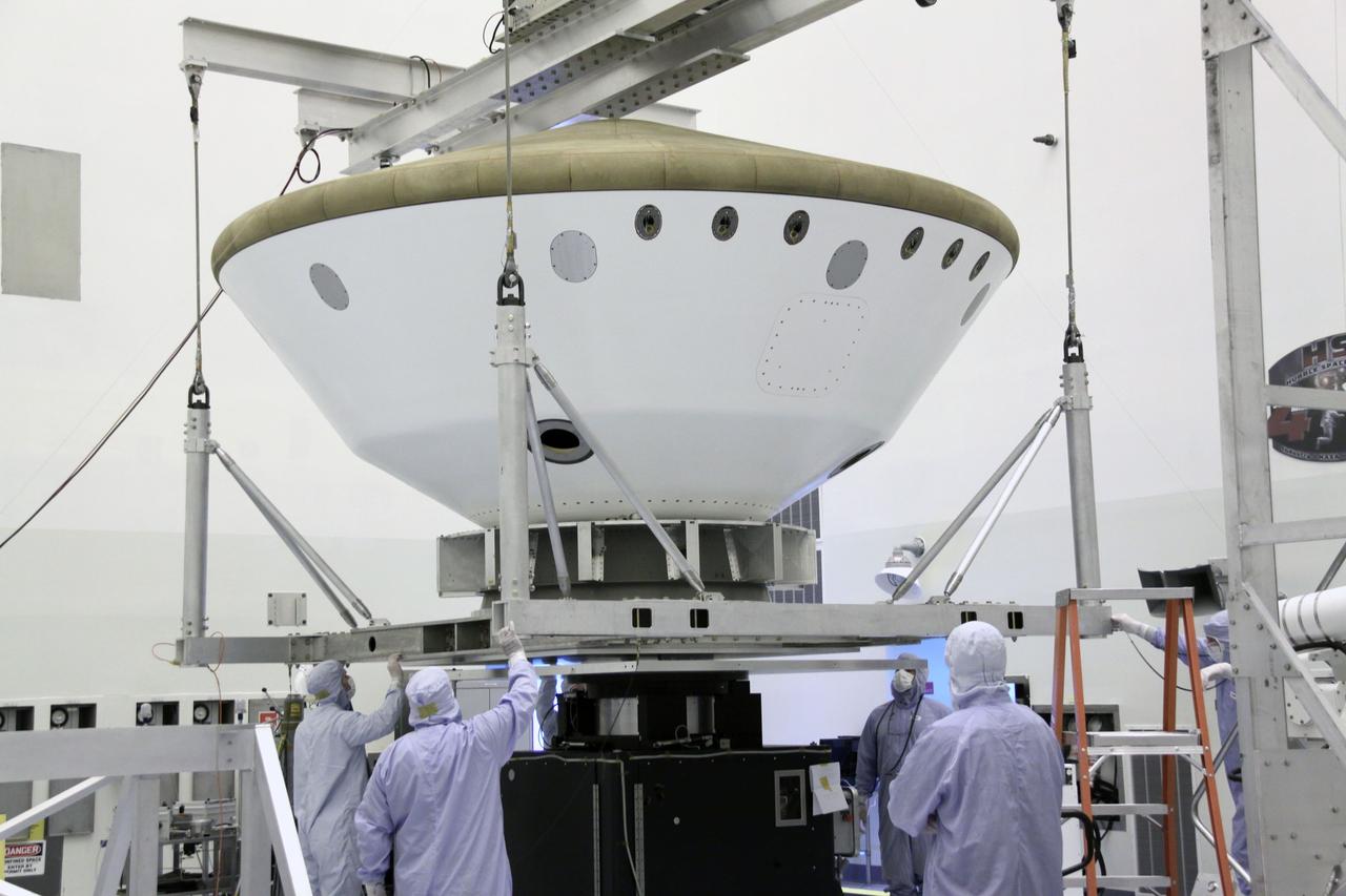 Cape Canaveral, Fla. -- At the Payload Hazardous Servicing Facility at NASA's Kennedy Space Center in Florida, technicians use an overhead crane to lower the aeroshell, a component of NASA's Mars Science Laboratory (MSL), onto a spin stand for testing. The aeroshell consists of the backshell which carries the parachute and several components used during later stages of entry, descent and landing, and the spacecraft's heat shield.        MSL's components include a compact car-sized rover, Curiosity, which has 10 science instruments designed to search for evidence on whether Mars has had environments favorable to microbial life, including chemical ingredients for life.  The unique rover will use a laser to look inside rocks and release its gasses so that the rover’s spectrometer can analyze and send the data back to Earth. Launch of MSL aboard a United Launch Alliance Atlas V rocket is scheduled for Nov. 25 from Space Launch Complex 41 on Cape Canaveral Air Force Station in Florida. For more information, visit http://www.nasa.gov/msl. Photo credit: NASA/Jack Pfaller
