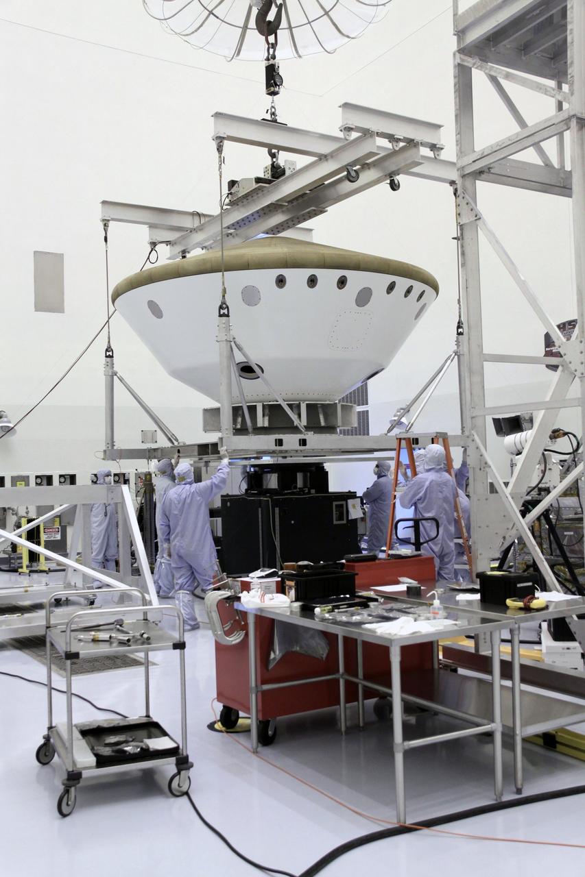 Cape Canaveral, Fla. -- At the Payload Hazardous Servicing Facility at NASA's Kennedy Space Center in Florida, technicians use an overhead crane to lower the aeroshell, a component of NASA's Mars Science Laboratory (MSL), onto a spin stand for testing. The aeroshell consists of the backshell which carries the parachute and several components used during later stages of entry, descent and landing, and the spacecraft's heat shield.        MSL's components include a compact car-sized rover, Curiosity, which has 10 science instruments designed to search for evidence on whether Mars has had environments favorable to microbial life, including chemical ingredients for life.  The unique rover will use a laser to look inside rocks and release its gasses so that the rover’s spectrometer can analyze and send the data back to Earth. Launch of MSL aboard a United Launch Alliance Atlas V rocket is scheduled for Nov. 25 from Space Launch Complex 41 on Cape Canaveral Air Force Station in Florida. For more information, visit http://www.nasa.gov/msl. Photo credit: NASA/Jack Pfaller