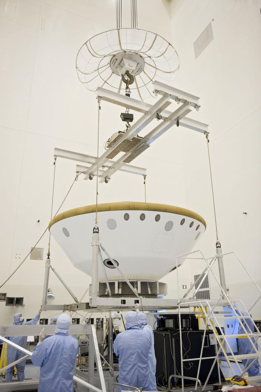 Cape Canaveral, Fla. -- At the Payload Hazardous Servicing Facility at NASA's Kennedy Space Center in Florida, technicians using an overhead crane, move the aeroshell, a component of NASA's Mars Science Laboratory (MSL), back to a work stand after a spin and balance test. The aeroshell consists of the backshell which carries the parachute and several components used during later stages of entry, descent and landing, and the spacecraft's heat shield. MSL's components include a compact car-sized rover, Curiosity, which has 10 science instruments designed to search for evidence on whether Mars has had environments favorable to microbial life, including chemical ingredients for life. The unique rover will use a laser to look inside rocks and release its gasses so that the rover’s spectrometer can analyze and send the data back to Earth. Launch of MSL aboard a United Launch Alliance Atlas V rocket is scheduled for Nov. 25 from Space Launch Complex 41 on Cape Canaveral Air Force Station in Florida. For more information, visit http://www.nasa.gov/msl. Photo credit: NASA/Kim Shiflett