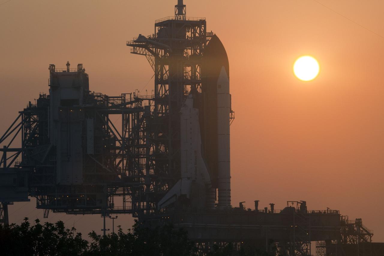 CAPE CANAVERAL, Fla. -- A hazy sun sets over Launch Pad 39A at NASA's Kennedy Space Center in Florida as space shuttle Atlantis awaits delivery of the Raffaello multi-purpose logistics module (MPLM) in its transportation canister. Once delivered, the canister will be lifted to the payload changeout room. The payload ground-handling mechanism then will be used to transfer Raffaello out of the canister into Atlantis' payload bay. Next, the rotating service structure that protects the shuttle from the elements and provides access will be rotated back into place.            Commander Chris Ferguson, Pilot Doug Hurley and Mission Specialists Sandra Magnus and Rex Walheim are targeted to lift off on Atlantis July 8, taking with them the MPLM packed with supplies, logistics and spare parts to the station. The STS-135 mission also will fly a system to investigate the potential for robotically refueling existing satellites and return a failed ammonia pump module to help NASA better understand the failure mechanism and improve pump designs for future systems. STS-135 will be the 33rd flight of Atlantis, the 37th shuttle mission to the space station, and the 135th and final mission of NASA's Space Shuttle Program. For more information visit, www.nasa.gov/mission_pages/shuttle/shuttlemissions/sts135/index.html. Photo credit: NASA/Frank Michaux