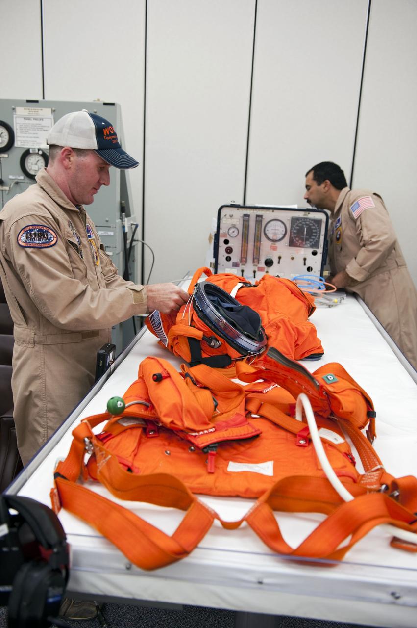CAPE CANAVERAL, Fla. -- In the Operations and Checkout Building at NASA's Kennedy Space Center in Florida, suit technicians Jeremy Spruell (left) and Ray Cuevas prepare the orange launch and landing suits for the STS-135 crew members. The crew is at Kennedy to participate in a launch countdown dress rehearsal called the Terminal Countdown Demonstration Test (TCDT) and related training in preparation for the upcoming STS-135 mission.               Atlantis and its crew are targeted to lift off July 8, taking with them the Raffaello multi-purpose logistics module packed with supplies and spare parts to the International Space Station. The STS-135 mission also will fly a system to investigate the potential for robotically refueling existing satellites and return a failed ammonia pump module to help NASA better understand the failure mechanism and improve pump designs for future systems. STS-135 will be the 33rd flight of Atlantis, the 37th shuttle mission to the space station, and the 135th and final mission of NASA's Space Shuttle Program. For more information visit, www.nasa.gov/mission_pages/shuttle/shuttlemissions/sts135/index.html.  Photo credit: NASA/Kim Shiflett