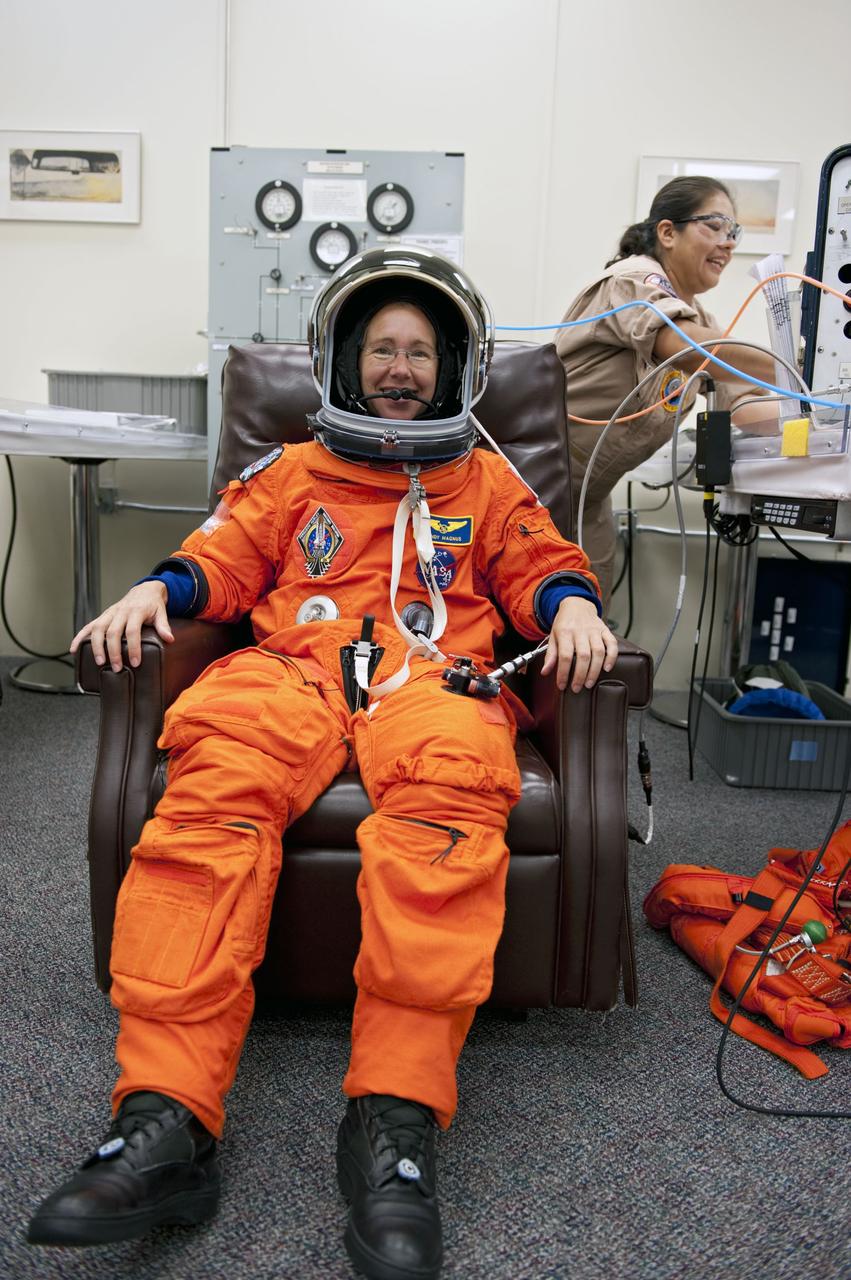 CAPE CANAVERAL, Fla. -- In the Operations and Checkout Building at NASA's Kennedy Space Center in Florida, Mission Specialist Sandy Magnus has her launch and landing suit checked by suit technician Cathy Cruz (background right). The STS-135 crew is at Kennedy to participate in a launch countdown dress rehearsal called the Terminal Countdown Demonstration Test (TCDT) and related training in preparation for the upcoming STS-135 mission.    Atlantis and its crew are targeted to lift off July 8, taking with them the Raffaello multi-purpose logistics module packed with supplies and spare parts to the International Space Station. The STS-135 mission also will fly a system to investigate the potential for robotically refueling existing satellites and return a failed ammonia pump module to help NASA better understand the failure mechanism and improve pump designs for future systems. STS-135 will be the 33rd flight of Atlantis, the 37th shuttle mission to the space station, and the 135th and final mission of NASA's Space Shuttle Program. For more information visit, www.nasa.gov/mission_pages/shuttle/shuttlemissions/sts135/index.html.  Photo credit: NASA/Kim Shiflett