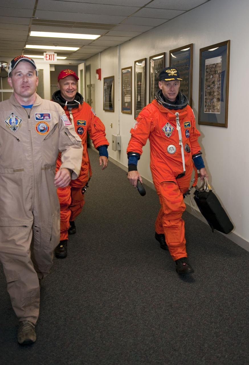 CAPE CANAVERAL, Fla. -- In the Operations and Checkout Building at NASA's Kennedy Space Center in Florida, Pilot Doug Hurley (center) and Commander Chris Ferguson are accompanied by suit technician Jeremy Spruell. Hurley and Ferguson are on their way to Kennedy's Shuttle Landing Facility to practice touch-and-go landing in the two Shuttle Training Aircrafts. The STS-135 crew is at Kennedy to participate in a launch countdown dress rehearsal called the Terminal Countdown Demonstration Test (TCDT) and related training in preparation for the upcoming STS-135 mission.      Atlantis and its crew are targeted to lift off July 8, taking with them the Raffaello multi-purpose logistics module packed with supplies and spare parts to the International Space Station. The STS-135 mission also will fly a system to investigate the potential for robotically refueling existing satellites and return a failed ammonia pump module to help NASA better understand the failure mechanism and improve pump designs for future systems. STS-135 will be the 33rd flight of Atlantis, the 37th shuttle mission to the space station, and the 135th and final mission of NASA's Space Shuttle Program. For more information visit, www.nasa.gov/mission_pages/shuttle/shuttlemissions/sts135/index.html.  Photo credit: NASA/Kim Shiflett