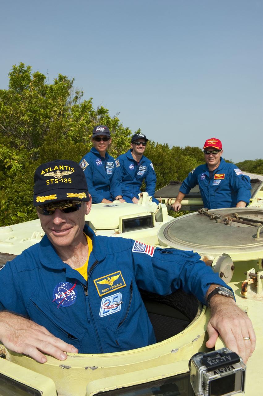 CAPE CANAVERAL, Fla. -- The STS-135 crew pause for a photo during their M113 armored personnel carrier training at NASA's Kennedy Space Center in Florida. Seen here are Commander Chris Ferguson (front), Mission Specialists Sandy Magnus, Rex Walheim and Pilot Doug Hurley (red cap). An M113 is kept at the foot of the launch pad in case an emergency exit from the launch pad is needed and every shuttle crew is trained on driving the vehicle before launch. The STS-135 crew is at Kennedy to participate in a launch countdown dress rehearsal called the Terminal Countdown Demonstration Test (TCDT) and related training.          Atlantis and its crew are targeted to lift off July 8, taking with them the Raffaello multi-purpose logistics module packed with supplies and spare parts to the International Space Station. The STS-135 mission also will fly a system to investigate the potential for robotically refueling existing satellites and return a failed ammonia pump module to help NASA better understand the failure mechanism and improve pump designs for future systems. STS-135 will be the 33rd flight of Atlantis, the 37th shuttle mission to the space station, and the 135th and final mission of NASA's Space Shuttle Program. For more information visit, www.nasa.gov/mission_pages/shuttle/shuttlemissions/sts135/index.html. Photo credit: NASA/Kim Shiflett