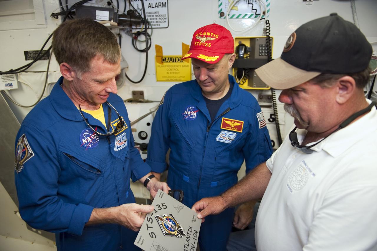 CAPE CANAVERAL, Fla. -- STS-135 Commander Chris Ferguson (left), Pilot Doug Hurley and Closeout Crew Lead Travis Tod Thompson with United Space Alliance, check out the plaque that will be placed in front of space shuttle Atlantis' hatch in the White Room at NASA Kennedy Space Center's Launch Pad 39A. An access arm supports the White Room that is in place against the shuttle which provides entry to the crew compartment. The astronauts are at Kennedy to participate in a launch countdown dress rehearsal called the Terminal Countdown Demonstration Test (TCDT) and related training. Atlantis and its crew are targeted to lift off July 8, taking with them the Raffaello multi-purpose logistics module packed with supplies and spare parts to the International Space Station. The STS-135 mission also will fly a system to investigate the potential for robotically refueling existing satellites and return a failed ammonia pump module to help NASA better understand the failure mechanism and improve pump designs for future systems. STS-135 will be the 33rd flight of Atlantis, the 37th shuttle mission to the space station, and the 135th and final mission of NASA's Space Shuttle Program. For more information visit, www.nasa.gov/mission_pages/shuttle/shuttlemissions/sts135/index.html. Photo credit: NASA/Kim Shiflett