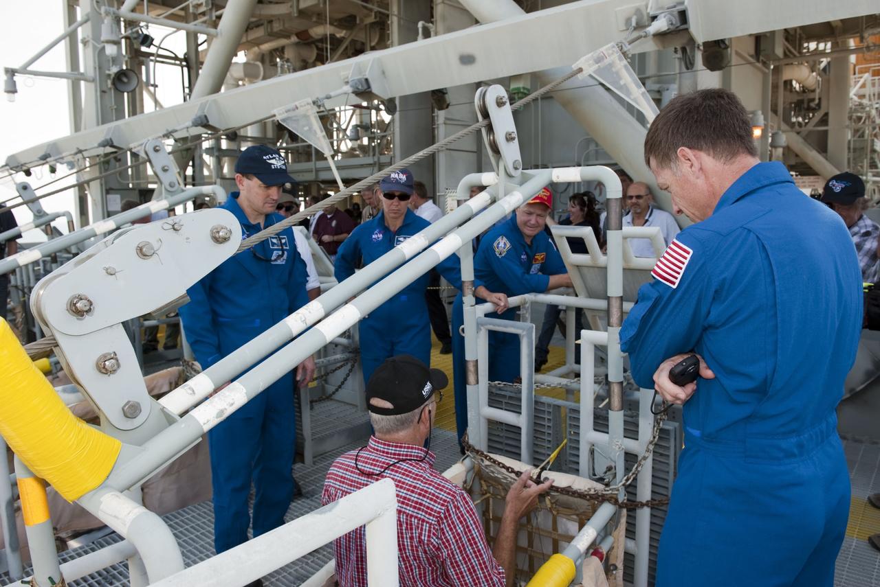 CAPE CANAVERAL, Fla. -- On Launch Pad 39A at NASA's Kennedy Space Center in Florida, space shuttle Atlantis' STS-135 crew members are instructed on the slidewire basket emergency exit system at the pad. From left are Mission Specialists Rex Walheim and Sandy Magnus, Pilot Doug Hurley and Commander Chris Ferguson.        The astronauts are at Kennedy to participate in a launch countdown dress rehearsal called the Terminal Countdown Demonstration Test (TCDT) and related training. Atlantis and its crew are targeted to lift off July 8, taking with them the Raffaello multi-purpose logistics module packed with supplies and spare parts to the International Space Station. The STS-135 mission also will fly a system to investigate the potential for robotically refueling existing satellites and return a failed ammonia pump module to help NASA better understand the failure mechanism and improve pump designs for future systems. STS-135 will be the 33rd flight of Atlantis, the 37th shuttle mission to the space station, and the 135th and final mission of NASA's Space Shuttle Program. For more information visit, www.nasa.gov/mission_pages/shuttle/shuttlemissions/sts135/index.html. Photo credit: NASA/Kim Shiflett