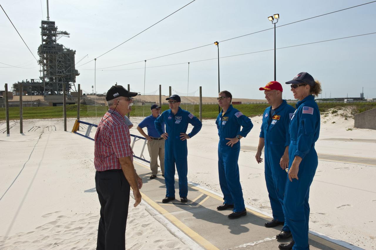 CAPE CANAVERAL, Fla. -- At Launch Pad 39A at NASA's Kennedy Space Center in Florida, members of space shuttle Atlantis' STS-135 crew receive instruction by the catch nets for the slidewire baskets at the base of the pad as part of the pad's emergency exit training. From right are Mission Specialist Sandy Magnus, Pilot Doug Hurley, Commander Chris Ferguson and Mission Specialist Rex Walheim.    The astronauts are at Kennedy to participate in a launch countdown dress rehearsal called the Terminal Countdown Demonstration Test (TCDT) and related training. Atlantis and its crew are targeted to lift off July 8, taking with them the Raffaello multi-purpose logistics module packed with supplies and spare parts to the International Space Station. The STS-135 mission also will fly a system to investigate the potential for robotically refueling existing satellites and return a failed ammonia pump module to help NASA better understand the failure mechanism and improve pump designs for future systems. STS-135 will be the 33rd flight of Atlantis, the 37th shuttle mission to the space station, and the 135th and final mission of NASA's Space Shuttle Program. For more information visit, www.nasa.gov/mission_pages/shuttle/shuttlemissions/sts135/index.html. Photo credit: NASA/Kim Shiflett