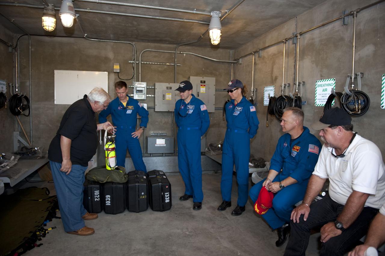 CAPE CANAVERAL, Fla. -- At Launch Pad 39A at NASA's Kennedy Space Center in Florida,  space shuttle Atlantis' STS-135 crew continue their emergency exit training in a bunker near the catch nets for the slidewire baskets at the base of the pad. The bunker would provide a safe haven for the astronauts if evacuation of the pad were required. From right are Pilot Doug Hurley (red cap), Mission Specialists Sandy Magnus and Rex Walheim, and Commander Chris Ferguson.        The astronauts are at Kennedy to participate in a launch countdown dress rehearsal called the Terminal Countdown Demonstration Test (TCDT) and related training. Atlantis and its crew are targeted to lift off July 8, taking with them the Raffaello multi-purpose logistics module packed with supplies and spare parts to the International Space Station. The STS-135 mission also will fly a system to investigate the potential for robotically refueling existing satellites and return a failed ammonia pump module to help NASA better understand the failure mechanism and improve pump designs for future systems. STS-135 will be the 33rd flight of Atlantis, the 37th shuttle mission to the space station, and the 135th and final mission of NASA's Space Shuttle Program. For more information visit, www.nasa.gov/mission_pages/shuttle/shuttlemissions/sts135/index.html. Photo credit: NASA/Kim Shiflett