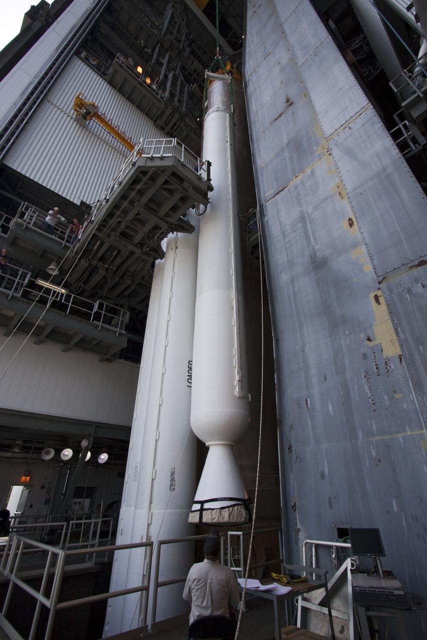 CAPE CANAVERAL, Fla. -- At Cape Canaveral Air Force Station in Florida, workers using an overhead crane lower the fifth and final solid rocket booster into the Vertical Integration Facility at Launch Complex 41. It then will be attached to the United Launch Alliance Atlas V booster stage, already at the pad.            NASA's Juno spacecraft is scheduled to launch aboard an Atlas V from Cape Canaveral, Fla. Aug. 5.The solar-powered spacecraft will orbit Jupiter's poles 33 times to find out more about the gas giant's origins, structure, atmosphere and magnetosphere and investigate the existence of a solid planetary core. For more information visit: www.nasa.gov/juno. Photo credit: NASA/Jim Grossmann
