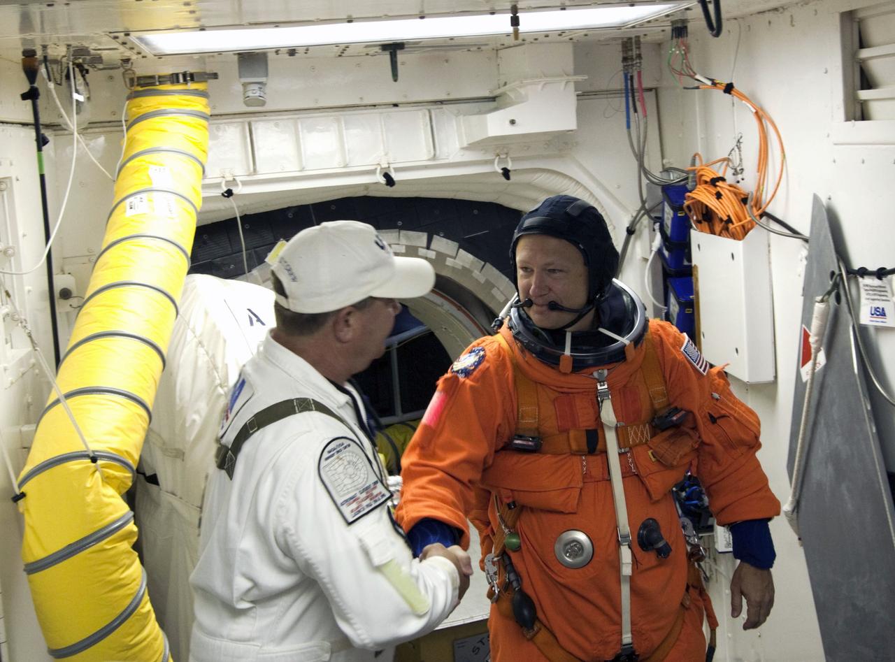 CAPE CANAVERAL, Fla. -- In the White Room at Launch Pad 39A at NASA's Kennedy Space Center in Florida, STS-135 Pilot Doug Hurley thanks Closeout Crew member Rene Arriens for his assistance as he prepares to board space shuttle Atlantis through the crew hatch in the background. Members of the Closeout Crew, in white uniforms, are there to assist astronauts with their launch-and-entry suits and the boarding process. The STS-135 crew members are at the pad to participate in a launch countdown simulation exercise.          As part of the Terminal Countdown Demonstration Test (TCDT), the crew members are strapped into their seats on Atlantis to practice the steps that will be taken on launch day. Shuttle Atlantis and its crew are targeted to lift off July 8, taking with them the Raffaello multi-purpose logistics module packed with supplies and spare parts to the International Space Station. The STS-135 mission also will fly a system to investigate the potential for robotically refueling existing satellites and return a failed ammonia pump module to help NASA better understand the failure mechanism and improve pump designs for future systems. STS-135 will be the 33rd flight of Atlantis, the 37th shuttle mission to the space station, and the 135th and final mission of NASA's Space Shuttle Program. For more information visit, www.nasa.gov/mission_pages/shuttle/shuttlemissions/sts135/index.html. Photo credit: NASA/Jim Grossmann