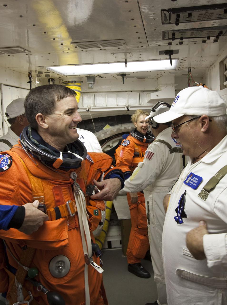 CAPE CANAVERAL, Fla. -- In the White Room at Launch Pad 39A at NASA's Kennedy Space Center in Florida, STS-135 Mission Specialist Rex Walheim prepares to board space shuttle Atlantis through the crew hatch in the background. Members of the Closeout Crew, in white uniforms, are there to assist astronauts with their launch-and-entry suits and the boarding process. Seen in the background is Mission Specialist Sandy Magnus speaking with a Closeout Crew member. The STS-135 crew is at the pad to participate in a launch countdown simulation exercise.            As part of the Terminal Countdown Demonstration Test (TCDT), the crew members are strapped into their seats on Atlantis to practice the steps that will be taken on launch day. Shuttle Atlantis and its crew are targeted to lift off July 8, taking with them the Raffaello multi-purpose logistics module packed with supplies and spare parts to the International Space Station. The STS-135 mission also will fly a system to investigate the potential for robotically refueling existing satellites and return a failed ammonia pump module to help NASA better understand the failure mechanism and improve pump designs for future systems. STS-135 will be the 33rd flight of Atlantis, the 37th shuttle mission to the space station, and the 135th and final mission of NASA's Space Shuttle Program. For more information visit, www.nasa.gov/mission_pages/shuttle/shuttlemissions/sts135/index.html. Photo credit: NASA/Jim Grossmann