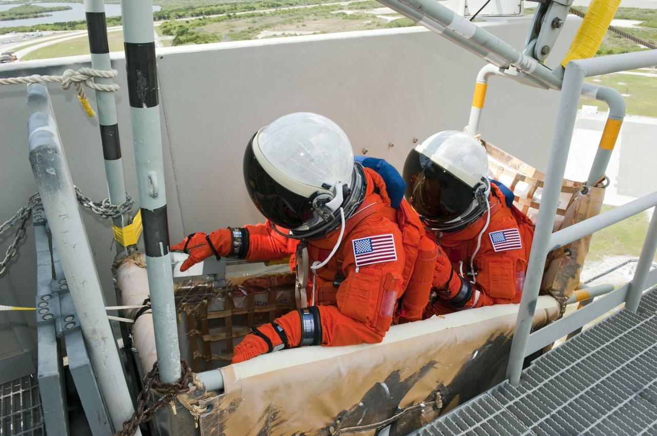 CAPE CANAVERAL, Fla. -- During simulated pad emergency exit training on Launch Pad 39A at NASA's Kennedy Space Center in Florida, STS-135 Mission Specialists Sandy Magnus (left) and Rex Walheim position themselves in a slidewire basket that would take them to a safe bunker below the pad in the unlikely event of an emergency.       The exercise is part of the Terminal Countdown Demonstration Test (TCDT) and related training. Atlantis and its crew are targeted to lift off July 8, taking with them the Raffaello multi-purpose logistics module packed with supplies and spare parts to the International Space Station. The STS-135 mission also will fly a system to investigate the potential for robotically refueling existing satellites and return a failed ammonia pump module to help NASA better understand the failure mechanism and improve pump designs for future systems. STS-135 will be the 33rd flight of Atlantis, the 37th shuttle mission to the space station, and the 135th and final mission of NASA's Space Shuttle Program. For more information visit, www.nasa.gov/mission_pages/shuttle/shuttlemissions/sts135/index.html. Photo credit: NASA/Kim Shiflett