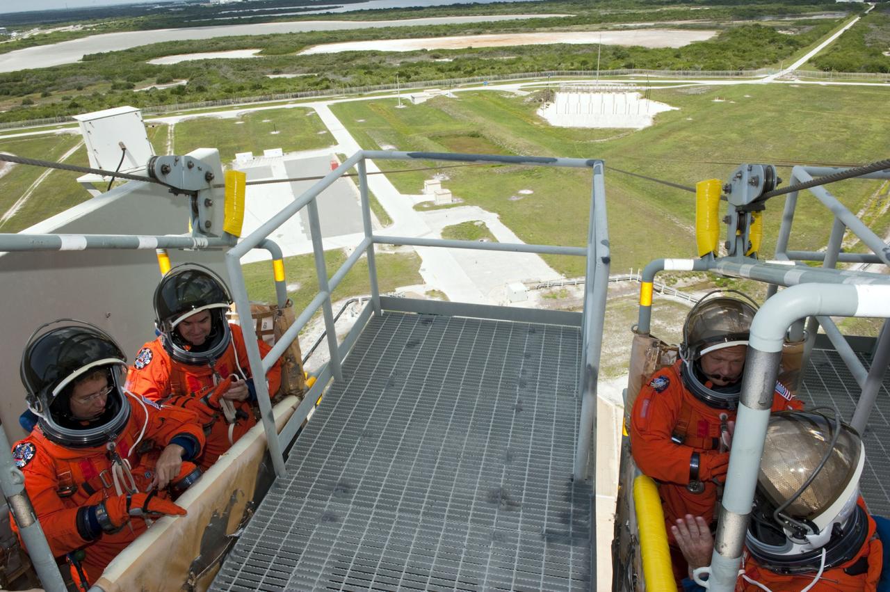 CAPE CANAVERAL, Fla. -- During simulated pad emergency exit training on Launch Pad 39A at NASA's Kennedy Space Center in Florida, STS-135 Commander Chris Ferguson (obscured) and Pilot Doug Hurley (right basket) and Mission Specialists Sandy Magnus and Rex Walheim (left basket) position themselves in slidewire baskets that would take them to a safe bunker below the pad in the unlikely event of an emergency.              The exercise is part of the Terminal Countdown Demonstration Test (TCDT) and related training. Atlantis and its crew are targeted to lift off July 8, taking with them the Raffaello multi-purpose logistics module packed with supplies and spare parts to the International Space Station. The STS-135 mission also will fly a system to investigate the potential for robotically refueling existing satellites and return a failed ammonia pump module to help NASA better understand the failure mechanism and improve pump designs for future systems. STS-135 will be the 33rd flight of Atlantis, the 37th shuttle mission to the space station, and the 135th and final mission of NASA's Space Shuttle Program. For more information visit, www.nasa.gov/mission_pages/shuttle/shuttlemissions/sts135/index.html. Photo credit: NASA/Kim Shiflett