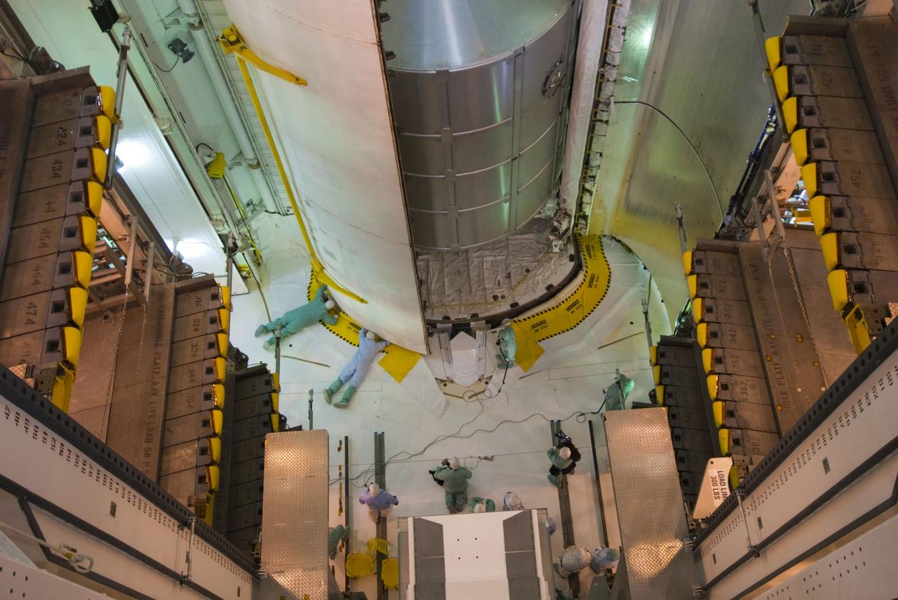 CAPE CANAVERAL, Fla. -- In the payload changeout room at Launch Pad 39A at NASA's Kennedy Space Center in Florida, technicians assist with the closure of space shuttle Atlantis' payload bay doors for flight. The payload arrived at the pad June 16 for installation into Atlantis and includes the Raffaello multi-purpose logistics module packed with supplies and spare parts for the International Space Station. The STS-135 mission also will fly a system to investigate the potential for robotically refueling existing satellites and return a failed ammonia pump module to help NASA better understand the failure mechanism and improve pump designs for future systems. Atlantis and its crew are scheduled to lift off at 11:26 a.m. EDT July 8. STS-135 will be the 33rd flight of Atlantis, the 37th shuttle mission to the space station, and the 135th and final mission of NASA's Space Shuttle Program. For more information, visit www.nasa.gov/shuttle. Photo credit: NASA/Jim Grossmann
