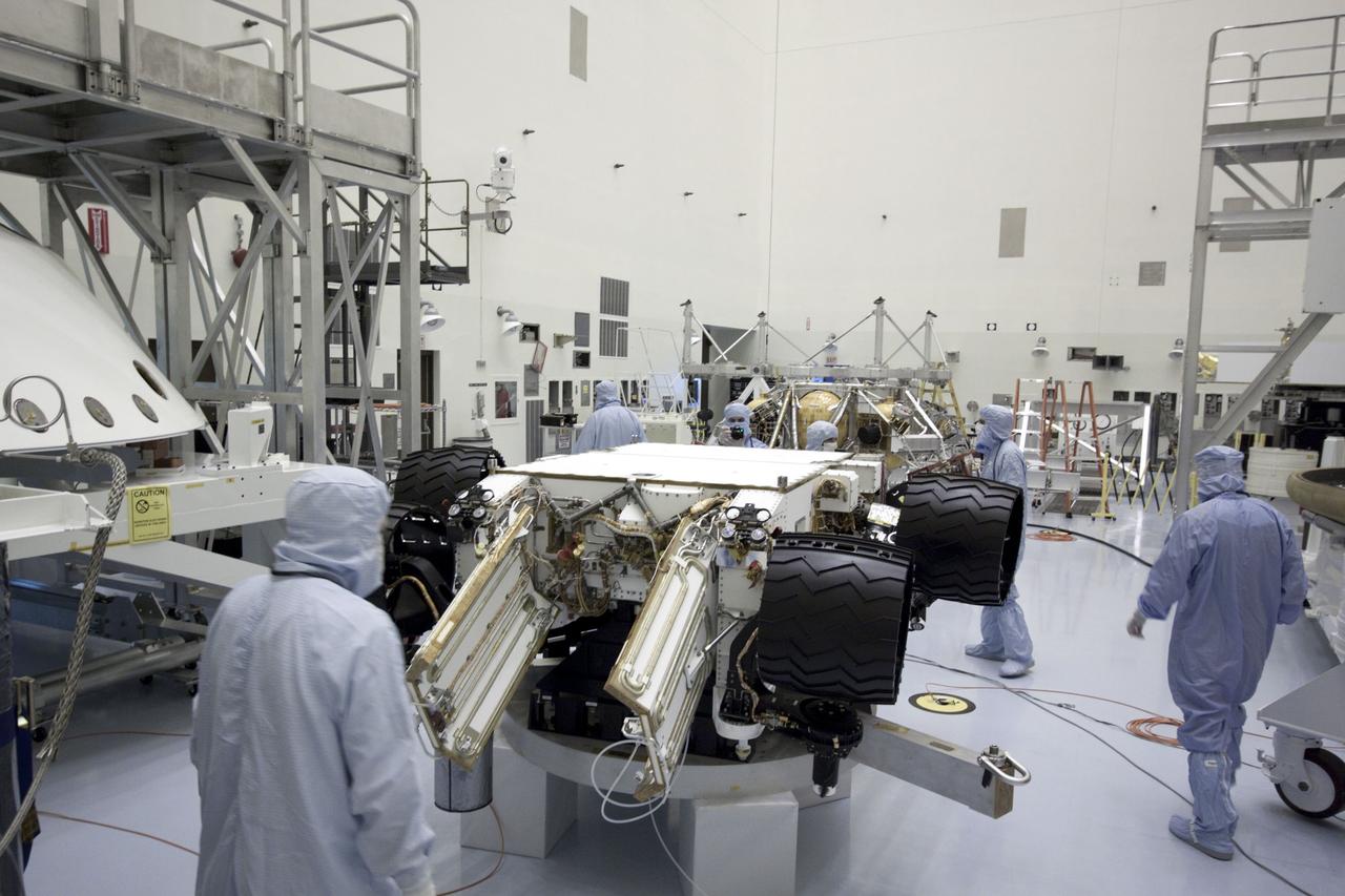 Cape Canaveral, Fla. -- At the Payload Hazardous Servicing Facility at NASA's Kennedy Space Center in Florida, NASA's Mars Science Laboratory (MSL) rover known as Curiosity, is secured on a work stand for processing. The spacecraft's backshell (left), which carries the parachute and several components used during later stages of entry, descent and landing, in addition is the rocket-powered descent stage (background), also is visible in the image.        A United Launch Alliance Atlas V-541 configuration will be used to loft MSL into space. Curiosity’s 10 science instruments are designed to search for evidence on whether Mars has had environments favorable to microbial life, including chemical ingredients for life.  The unique rover will use a laser to look inside rocks and release its gasses so that the rover’s spectrometer can analyze and send the data back to Earth. MSL is scheduled to launch from Cape Canaveral Air Force Station in Florida Nov. 25 with a window extending to Dec. 18 and arrival at Mars Aug. 2012. For more information, visit http://www.nasa.gov/msl. Photo credit: NASA/Jim Grossmann