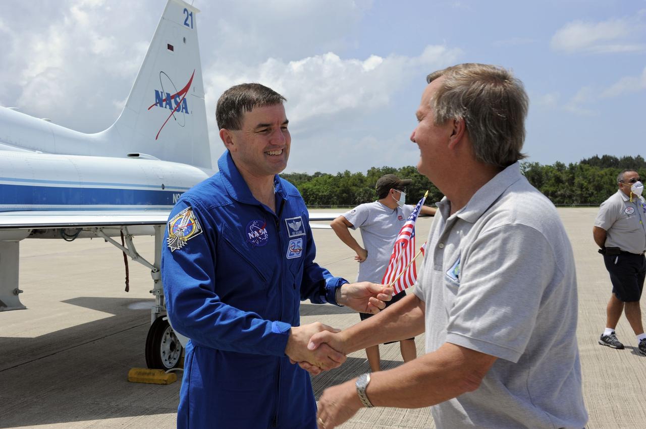 CAPE CANAVERAL, Fla. -- On the Shuttle Landing Facility at NASA's Kennedy Space Center in Florida,  STS-135 Mission Specialist Rex Walheim is greeted by Shuttle Launch Director Mike Leinbach.            The STS-135 crew members arrived at Kennedy at about 2:30 p.m. EDT on July 4 for final preparations for space shuttle Atlantis' STS-135 mission to the International Space Station. Atlantis is scheduled to lift off on July 8 to deliver the Raffaello multi-purpose logistics module packed with supplies and spare parts to the station. The STS-135 mission also will fly a system to investigate the potential for robotically refueling existing satellites and return a failed ammonia pump module to help NASA better understand the failure mechanism and improve pump designs for future systems. STS-135 will be the 33rd flight of Atlantis, the 37th shuttle mission to the space station, and the 135th and final mission of NASA's Space Shuttle Program. For more information visit, www.nasa.gov/mission_pages/shuttle/shuttlemissions/sts135/index.html. Photo credit: NASA/Kim Shiflett