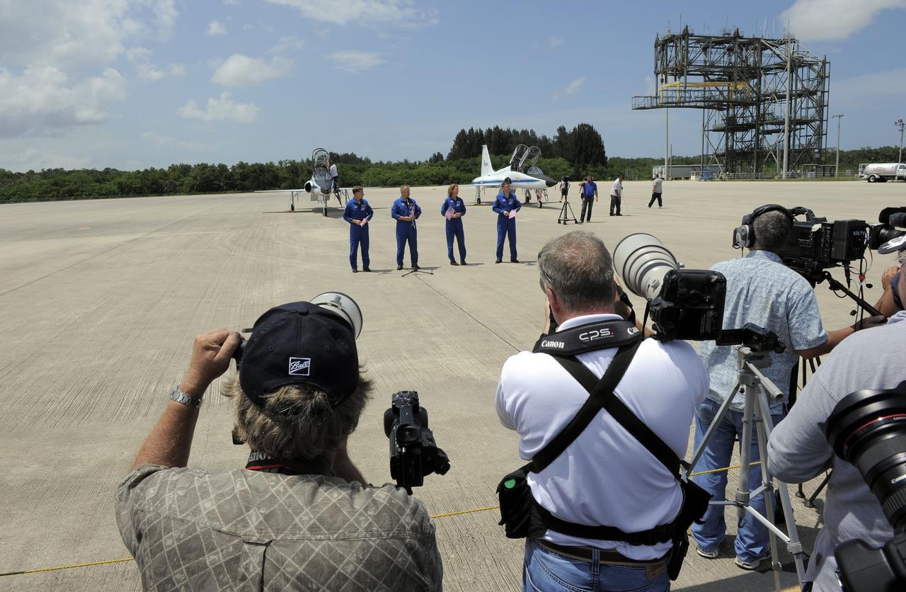 CAPE CANAVERAL, Fla. -- The STS-135 crew speak to media after arriving at the Shuttle Landing Facility at NASA's Kennedy Space Center in Florida. From left are Commander Chris Ferguson, Pilot Doug Hurley and Mission Specialists Sandy Magnus and Rex Walheim.      The STS-135 crew members arrived at Kennedy at about 2:30 p.m. EDT on July 4 for final preparations for space shuttle Atlantis' STS-135 mission to the International Space Station. Atlantis is scheduled to lift off on July 8 to deliver the Raffaello multi-purpose logistics module packed with supplies and spare parts to the station. The STS-135 mission also will fly a system to investigate the potential for robotically refueling existing satellites and return a failed ammonia pump module to help NASA better understand the failure mechanism and improve pump designs for future systems. STS-135 will be the 33rd flight of Atlantis, the 37th shuttle mission to the space station, and the 135th and final mission of NASA's Space Shuttle Program. For more information visit, www.nasa.gov/mission_pages/shuttle/shuttlemissions/sts135/index.html. Photo credit: NASA/Kim Shiflett