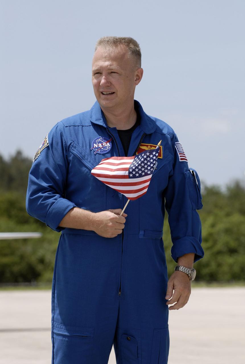 CAPE CANAVERAL, Fla. -- STS-135 Pilot Doug Hurley, holding an American flag to commemorate the U.S. Independence Day holiday, pauses for a photo at the Shuttle Landing Facility at NASA's Kennedy Space Center in Florida. The STS-135 astronauts arrived at Kennedy about 2:30 p.m. EDT on July 4 for final preparations for space shuttle Atlantis' STS-135 mission to the International Space Station. Atlantis is scheduled to lift off on July 8 to deliver the Raffaello multi-purpose logistics module packed with supplies and spare parts to the station. The STS-135 mission also will fly a system to investigate the potential for robotically refueling existing satellites and return a failed ammonia pump module to help NASA better understand the failure mechanism and improve pump designs for future systems. STS-135 will be the 33rd flight of Atlantis, the 37th shuttle mission to the space station, and the 135th and final mission of NASA's Space Shuttle Program. For more information visit, www.nasa.gov/mission_pages/shuttle/shuttlemissions/sts135/index.html. Photo credit: NASA/Kim Shiflett