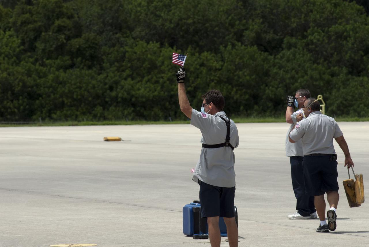 CAPE CANAVERAL, Fla. -- On the Shuttle Landing Facility (SLF) at NASA's Kennedy Space Center in Florida, Kennedy SLF crews signal STS-135 Commander Chris Ferguson and Mission Specialist Sandy Magnus to stop on the tarmac. The STS-135 astronauts arrived at Kennedy about 2:30 p.m. EDT on July 4 for final preparations for space shuttle Atlantis' STS-135 mission to the International Space Station. Atlantis is scheduled to lift off on July 8 to deliver the Raffaello multi-purpose logistics module packed with supplies and spare parts to the station. The STS-135 mission also will fly a system to investigate the potential for robotically refueling existing satellites and return a failed ammonia pump module to help NASA better understand the failure mechanism and improve pump designs for future systems. STS-135 will be the 33rd flight of Atlantis, the 37th shuttle mission to the space station, and the 135th and final mission of NASA's Space Shuttle Program. For more information visit, www.nasa.gov/mission_pages/shuttle/shuttlemissions/sts135/index.html. Photo credit: NASA/Jim Grossmann