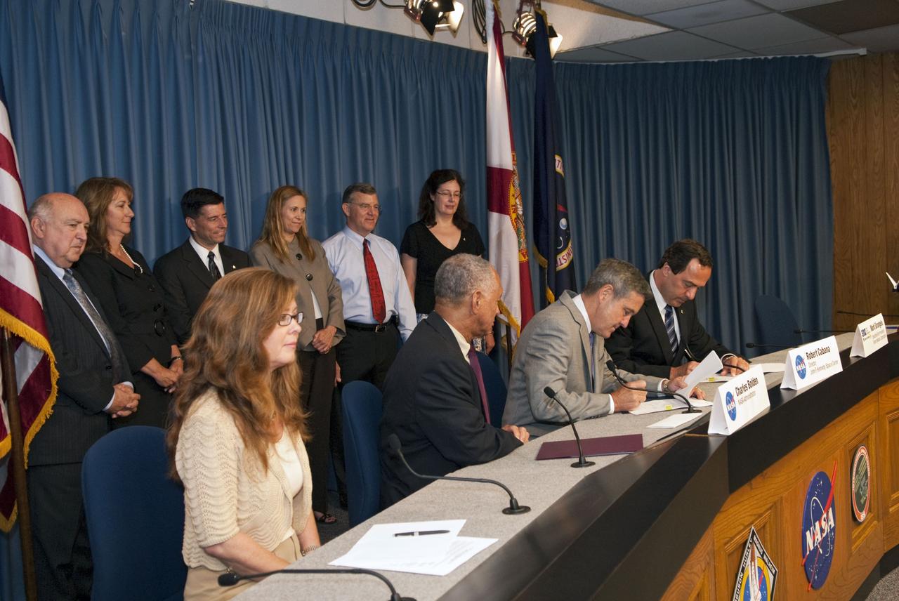 CAPE CANAVERAL, Fla. -- NASA and Sierra Nevada Space Systems (SNSS) of Sparks, Nev., sign a Space Act Agreement that will offer the company technical capabilities from Kennedy Space Center's uniquely skilled work force. Sitting, from left, are Kennedy Public Affairs Director Lisa Malone; NASA Administrator Charlie Bolden; Kennedy Center Director Bob Cabana; and Mark Sirangelo, head of Sierra Nevada. Standing, from left, are Frank DiBello, president of Space Florida; Joyce Riquelme, manager of Kennedy's Center Planning and Development Office; John Curry, director of Sierra Nevada's Systems Integration, Test and Operations; Kennedy Deputy Director Janet Petro; Jim Voss, vice president of Sierra Nevada's Space Exploration Systems; and Merri Sanchez, senior director of Sierra Nevada's Space Exploration Systems. Kennedy will help Sierra Nevada with the ground operations support of its lifting body reusable spacecraft called "Dream Chaser," which resembles a smaller version of the space shuttle orbiter.          The spacecraft would carry as many as seven astronauts to the space station. Through the new agreement, Kennedy's work force will use its experience of processing the shuttle fleet for 30 years to help Sierra Nevada define and execute Dream Chaser's launch preparations and post-landing activities. In 2010 and 2011, Sierra Nevada was awarded grants as part of the initiative to stimulate the private sector in developing and demonstrating human spaceflight capabilities for NASA's Commercial Crew Program. The goal of the program, which is based in Florida at Kennedy, is to facilitate the development of a U.S. commercial crew space transportation capability by achieving safe, reliable and cost-effective access to and from the space station and future low Earth orbit destinations. Photo credit: NASA/Jim Grossmann