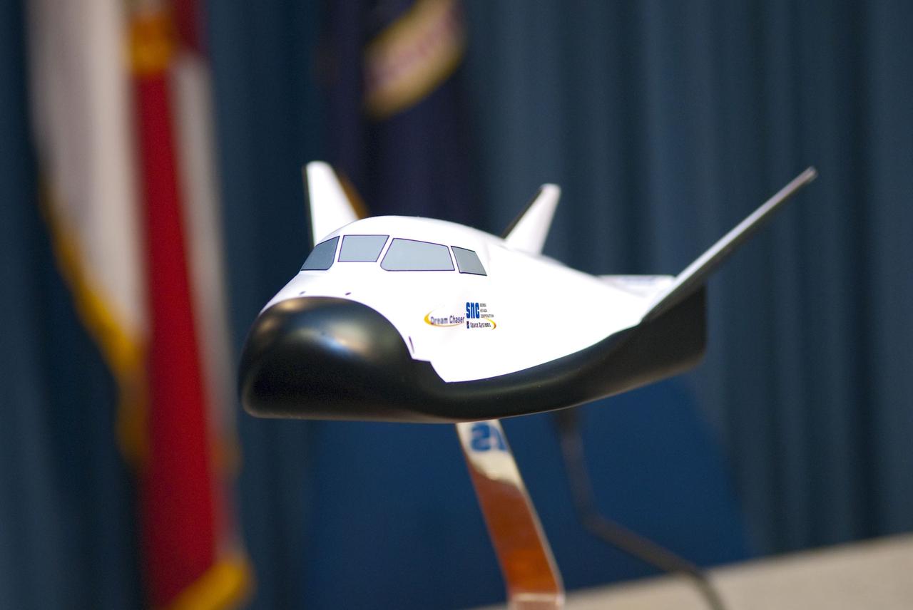 CAPE CANAVERAL, Fla. -- Sierra Nevada Space Systems (SNSS) of Sparks, Nev., and NASA signed a Space Act Agreement that will offer the company technical capabilities from Kennedy's uniquely skilled work force. Kennedy will help Sierra Nevada with the ground operations support of its lifting body reusable spacecraft called "Dream Chaser." The spacecraft, seen here as a display, resembles a smaller version of the space shuttle orbiter.      The spacecraft would carry as many as seven astronauts to the space station. Through the new agreement, Kennedy's work force will use its experience of processing the shuttle fleet for 30 years to help Sierra Nevada define and execute Dream Chaser's launch preparations and post-landing activities. In 2010 and 2011, Sierra Nevada was awarded grants as part of the initiative to stimulate the private sector in developing and demonstrating human spaceflight capabilities for NASA's Commercial Crew Program. The goal of the program, which is based in Florida at Kennedy, is to facilitate the development of a U.S. commercial crew space transportation capability by achieving safe, reliable and cost-effective access to and from the space station and future low Earth orbit destinations. Photo credit: NASA/Jim Grossmann