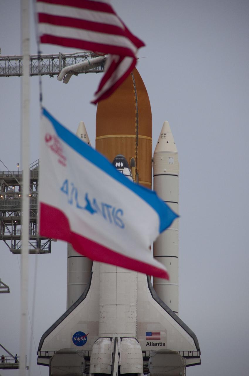 CAPE CANAVERAL, Fla. -- Flags wave briskly at Launch Pad 39A at NASA's Kennedy Space Center in Florida as space shuttle Atlantis is revealed following the move of the rotating service structure (RSS). The structure provides weather protection and access to the shuttle while it awaits liftoff on the pad. RSS "rollback" marks a major milestone in Atlantis' STS-135 mission countdown.        Atlantis and its crew of four; Commander Chris Ferguson, Pilot Doug Hurley and Mission Specialists Sandy Magnus and Rex Walheim, are scheduled to lift off at 11:26 a.m. EDT on July 8 to deliver the Raffaello multi-purpose logistics module packed with supplies and spare parts to the International Space Station. Atlantis also will fly the Robotic Refueling Mission experiment that will investigate the potential for robotically refueling existing satellites in orbit. In addition, Atlantis will return with a failed ammonia pump module to help NASA better understand the failure mechanism and improve pump designs for future systems. STS-135 will be the 33rd flight of Atlantis, the 37th shuttle mission to the space station, and the 135th and final mission of NASA's Space Shuttle Program. For more information visit, www.nasa.gov/mission_pages/shuttle/shuttlemissions/sts135/index.html. Photo credit: NASA/Troy Cryder