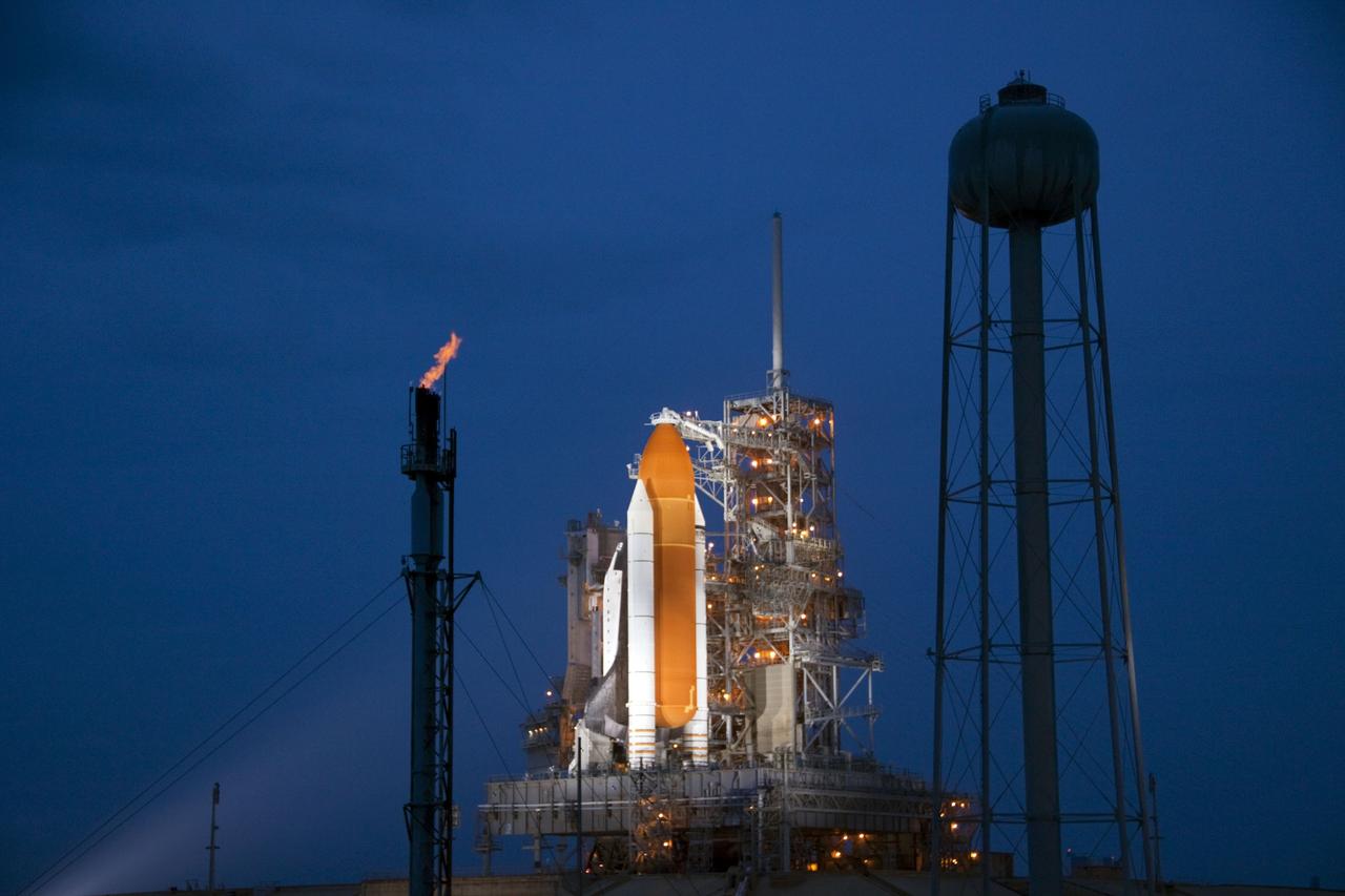 CAPE CANAVERAL, Fla. -- Space shuttle Atlantis is revealed on Launch Pad 39A at NASA's Kennedy Space Center in Florida bathed in xenon lights following the move of the rotating service structure (RSS). The structure provides weather protection and access to the shuttle while it awaits liftoff on the pad. The tower at left is used for safely burning off any excess hydrogen while the shuttle is on the pad prior to launch. To the right of the pad is the 300,000-gallon water tower that provides the water used for sound suppression on the pad during liftoff.  RSS retract marks a major milestone in Atlantis' STS-135 mission countdown.                Atlantis and its crew of four; Commander Chris Ferguson, Pilot Doug Hurley, Mission Specialists Sandy Magnus and Rex Walheim will lift off at 11:26 a.m. EDT on July 8 to deliver the Raffaello multi-purpose logistics module packed with supplies and spare parts for the International Space Station. Atlantis also will fly the Robotic Refueling Mission experiment that will investigate the potential for robotically refueling existing satellites in orbit. In addition, Atlantis will return with a failed ammonia pump module to help NASA better understand the failure mechanism and improve pump designs for future systems. STS-135 is the 33rd flight of Atlantis, the 37th shuttle mission to the space station, and the 135th and final mission of NASA's Space Shuttle Program. For more information, visit www.nasa.gov/mission_pages/shuttle/shuttlemissions/sts135/index.html. Photo credit: Jim Grossmann
