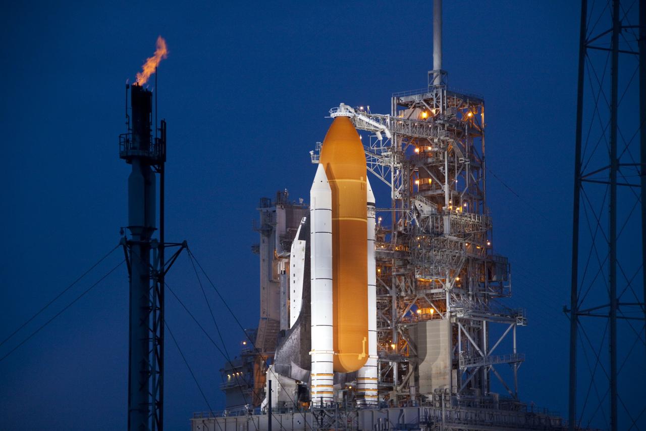 CAPE CANAVERAL, Fla. -- Space shuttle Atlantis is revealed on Launch Pad 39A at NASA's Kennedy Space Center in Florida bathed in xenon lights following the move of the rotating service structure (RSS). The structure provides weather protection and access to the shuttle while it awaits liftoff on the pad. The tower at left is used for safely burning off any excess hydrogen while the shuttle is on the pad prior to launch.  RSS retract marks a major milestone in Atlantis' STS-135 mission countdown.                Atlantis and its crew of four; Commander Chris Ferguson, Pilot Doug Hurley, Mission Specialists Sandy Magnus and Rex Walheim will lift off at 11:26 a.m. EDT on July 8 to deliver the Raffaello multi-purpose logistics module packed with supplies and spare parts for the International Space Station. Atlantis also will fly the Robotic Refueling Mission experiment that will investigate the potential for robotically refueling existing satellites in orbit. In addition, Atlantis will return with a failed ammonia pump module to help NASA better understand the failure mechanism and improve pump designs for future systems. STS-135 is the 33rd flight of Atlantis, the 37th shuttle mission to the space station, and the 135th and final mission of NASA's Space Shuttle Program. For more information, visit www.nasa.gov/mission_pages/shuttle/shuttlemissions/sts135/index.html. Photo credit: Jim Grossmann